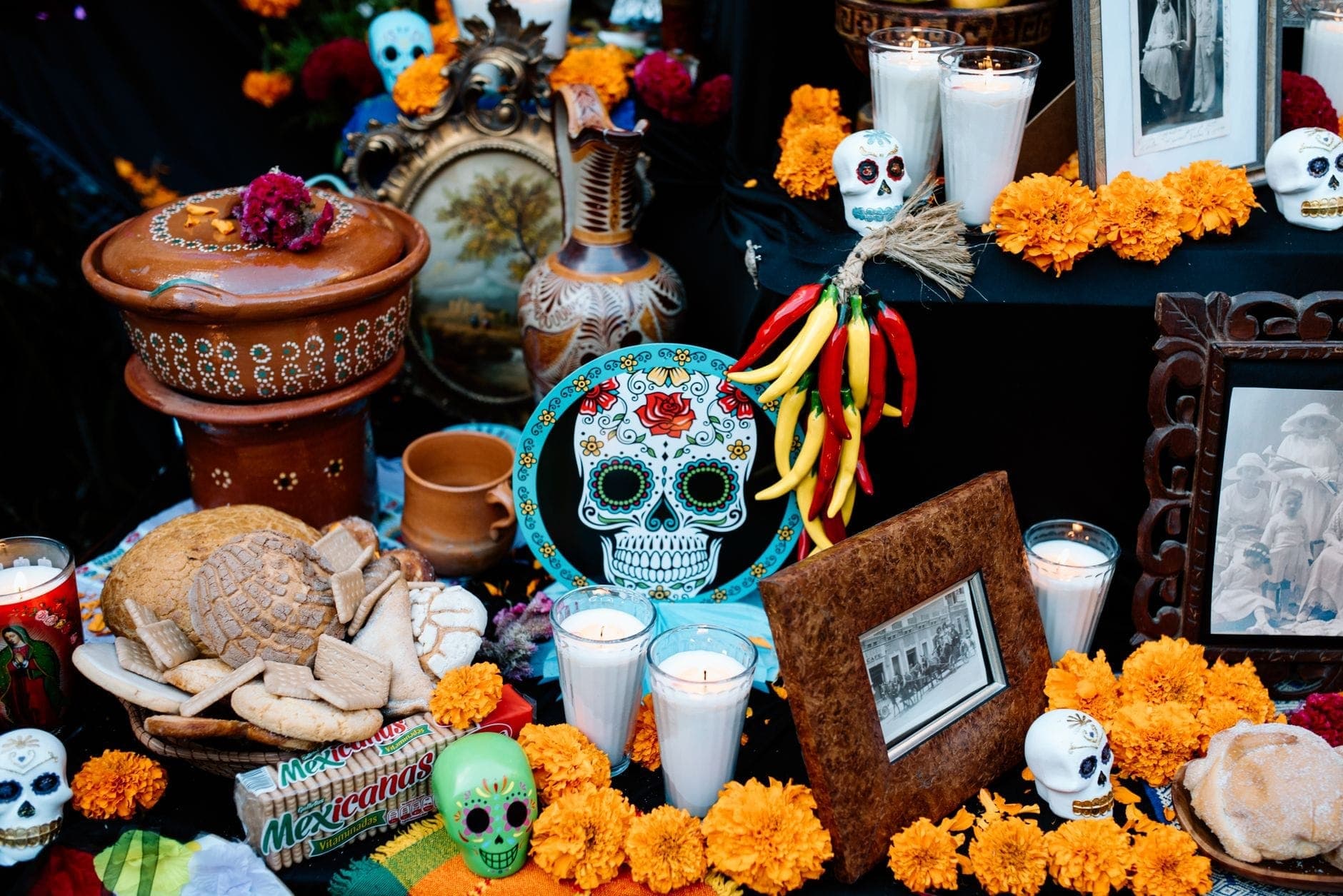 แท่นบูชา Día de los Muertos อันสดใสประดับด้วยดอกดาวเรือง เทียน กะโหลกน้ำตาล รูปถ่าย และขนมปังแบบดั้งเดิมในพื้นที่สาธารณะหรือทางวัฒนธรรม