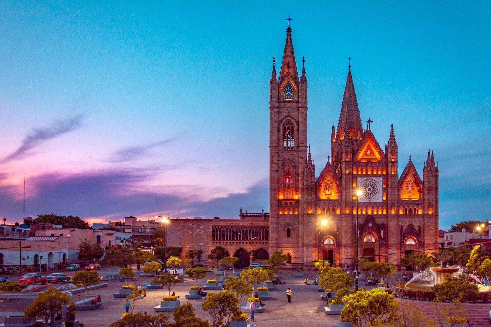 วิวกว้างของ Templo Expiatorio ในกัวดาลาฮาราช่วงพระอาทิตย์ตกดิน พร้อมด้านหน้าสไตล์โกธิกที่สว่างไสวและลานกว้างด้านหน้า