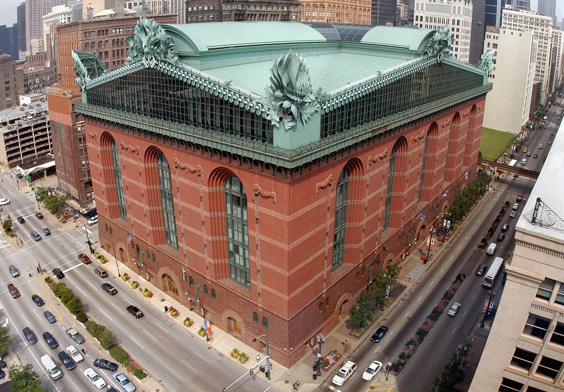 Aerial view of the Harold Washington Library Center in Chicago, showing its massive red brick facade and distinctive green roof ornaments.