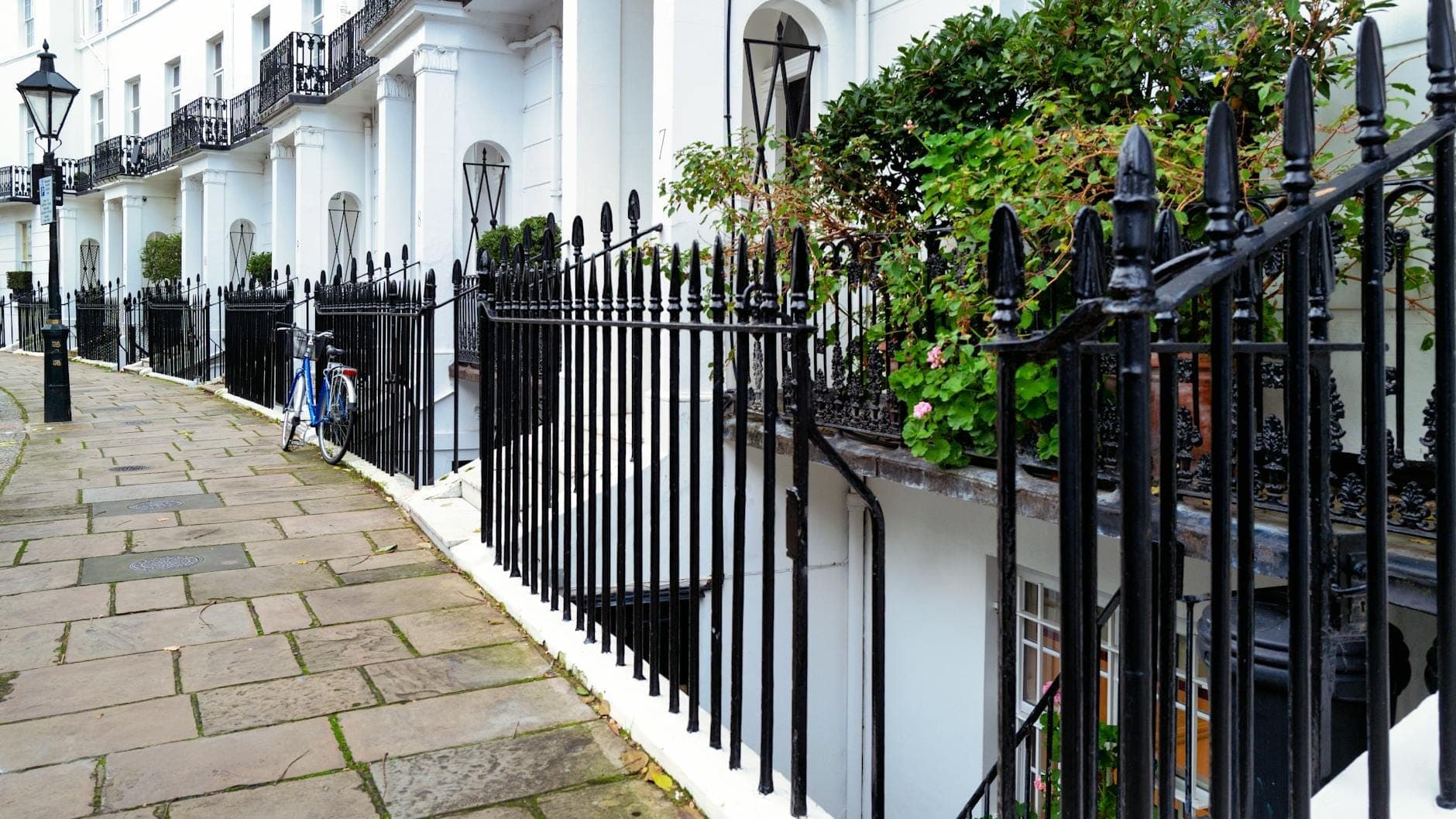 Eine georgianische Häuserzeile mit weißen Stadthäusern, schwarzen Schmiedeeisengittern und einem ruhigen Gartensquare in London.