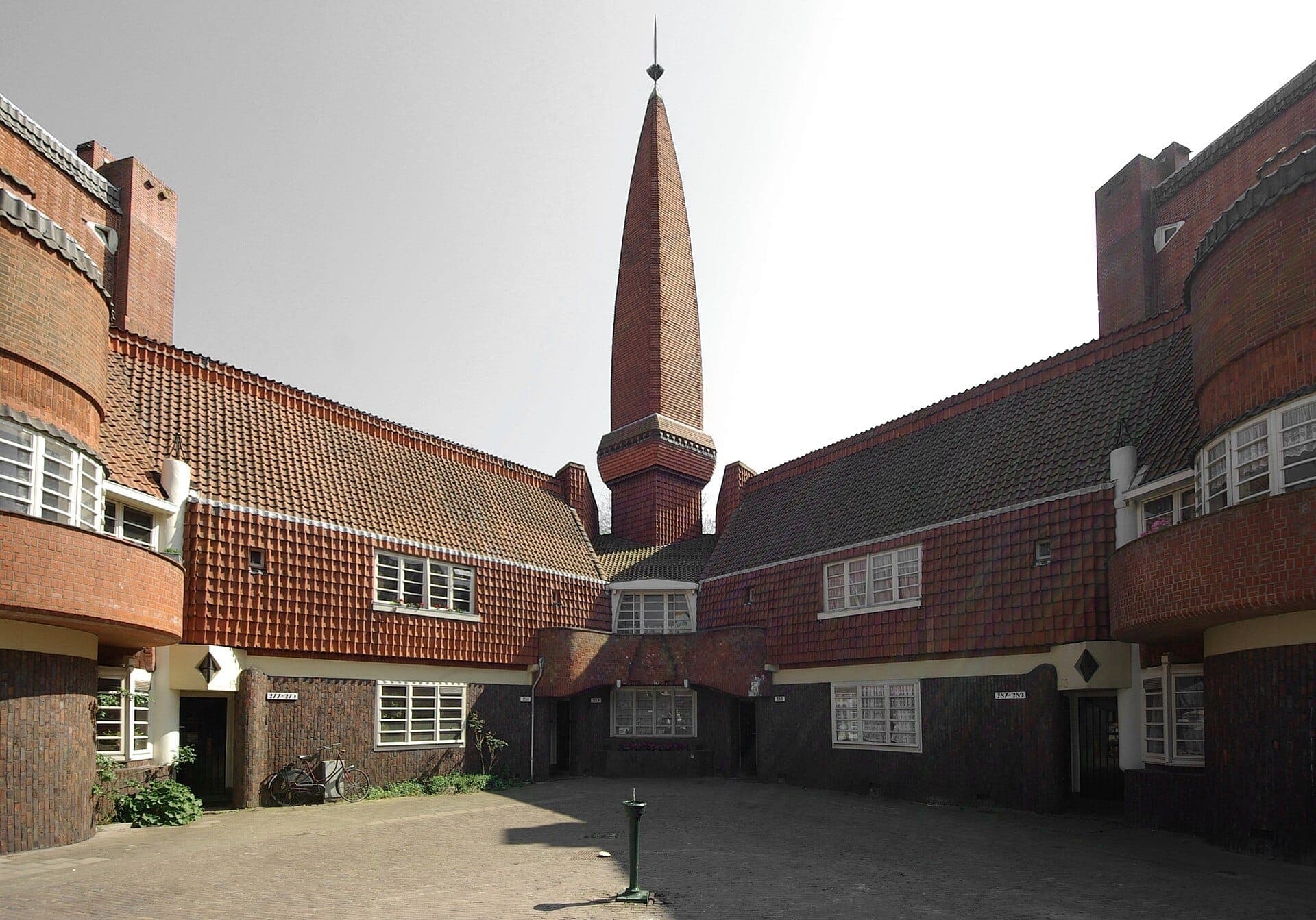 Außenansicht des Museum Het Schip mit seinem markanten Mauerwerk, den geschwungenen Fenstern und dem zentralen Turm bei klarem Tageslicht in Amsterdam.