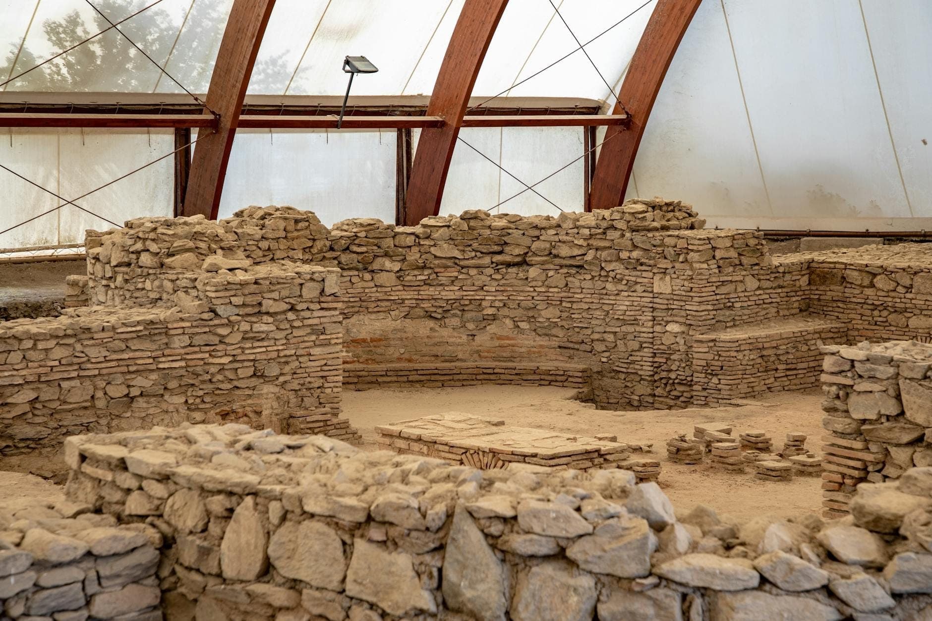 Blick auf antike Steinruinen unter Schutzdach, mit niedrigen Mauern und archäologischer Ausgrabungsstätte auf Kreta.