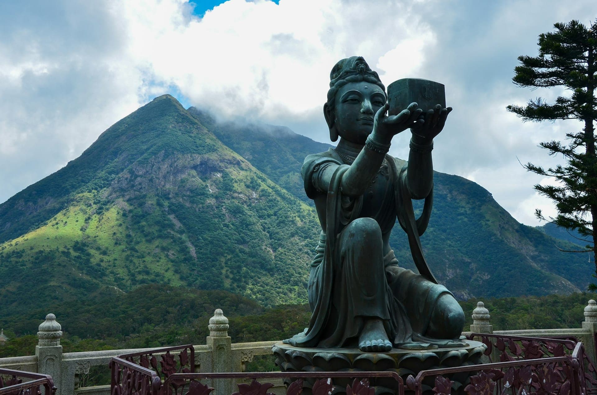 Buddhist statue on Lantau Island with green mountains in the background, Hong Kong