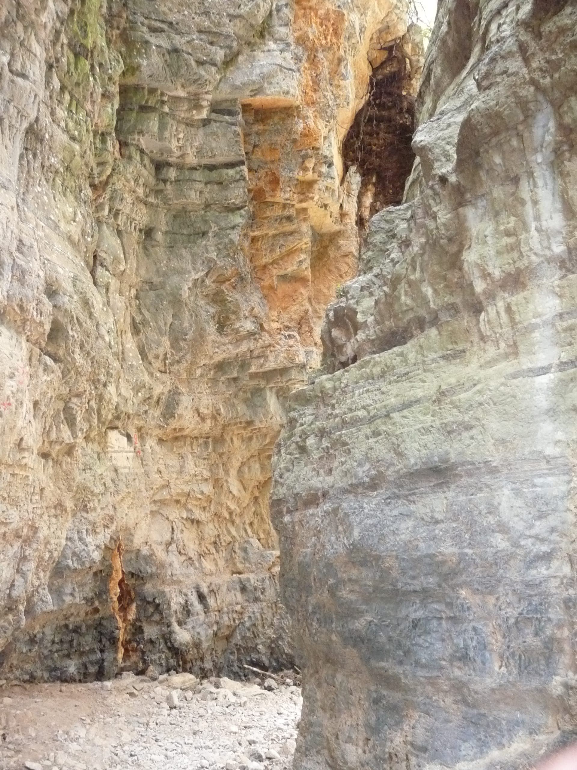 Senkrechte Kalksteinwände der Imbros-Schlucht auf Kreta, mit rauer Felsstruktur und einem schmalen, felsigen Pfad im natürlichen Tageslicht.
