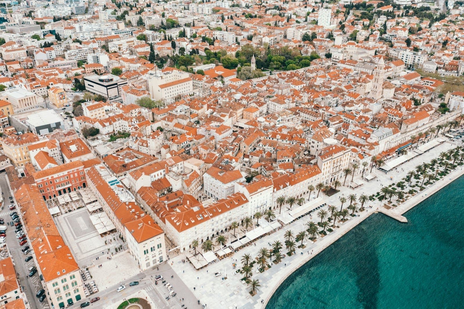 Vista aerea di Split, in Croazia, con i tetti in terracotta, il lungomare Riva fiancheggiato da palme e le acque cristalline dell'Adriatico.