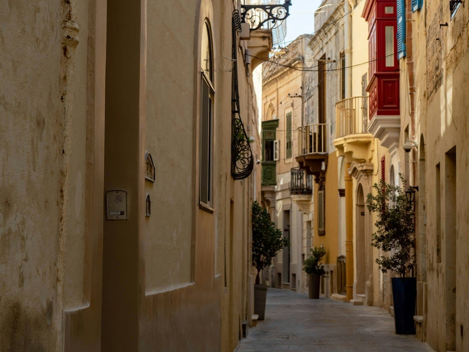 Enge Steinstraße in Birgu, Malta, gesäumt von bunten Balkonen und Topfpflanzen. Die charmante, historische Atmosphäre passt perfekt zur Umgebung der Three Cities.