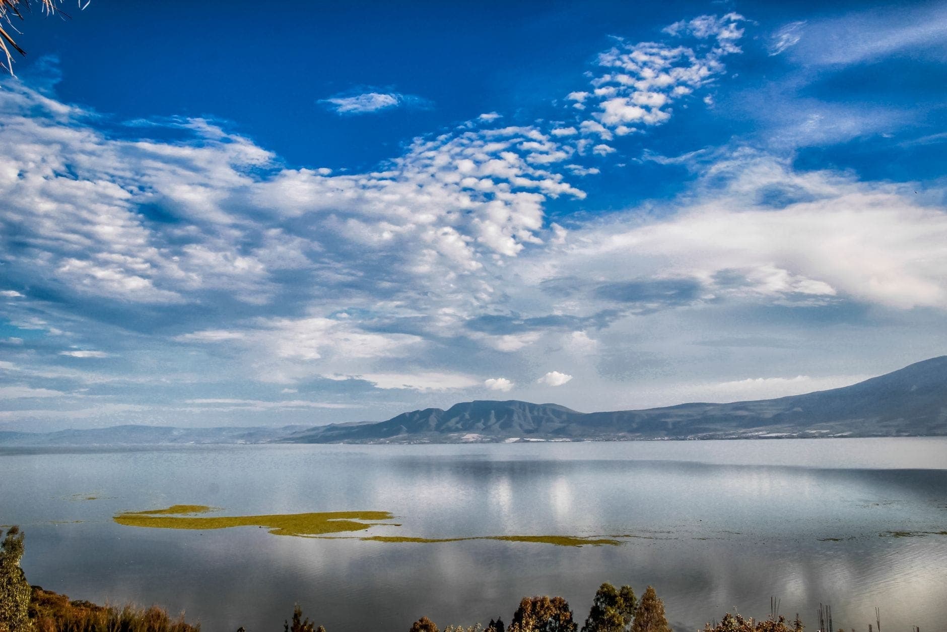 มุมกว้างของ Lago de Chapala ทะเลสาบสงบ มีเกาะเล็กๆ เมฆสวย เขาไกลตัดท้องฟ้าสีน้ำเงินสดใส