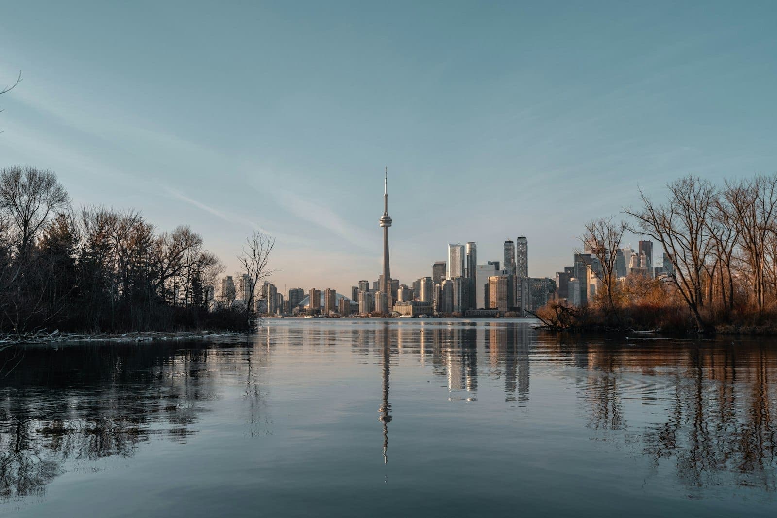 Skyline di Toronto vista dall'altra parte dell'acqua con alberi su entrambi i lati, che evidenzia la posizione geografica del lago Ontario.