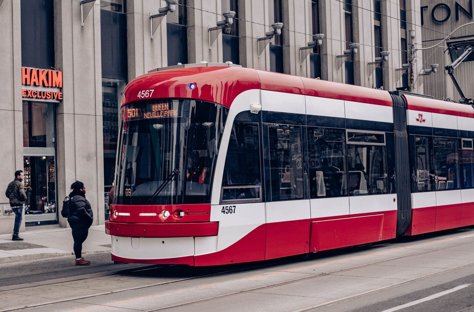 Tram di Toronto fermo a una piattaforma nel centro città con persone che salgono e scendono su una strada urbana.