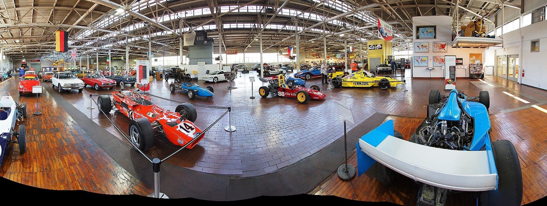 Wide view of vintage race cars and classic vehicles displayed inside Lane Motor Museum's spacious, sunlit industrial showroom in Nashville.