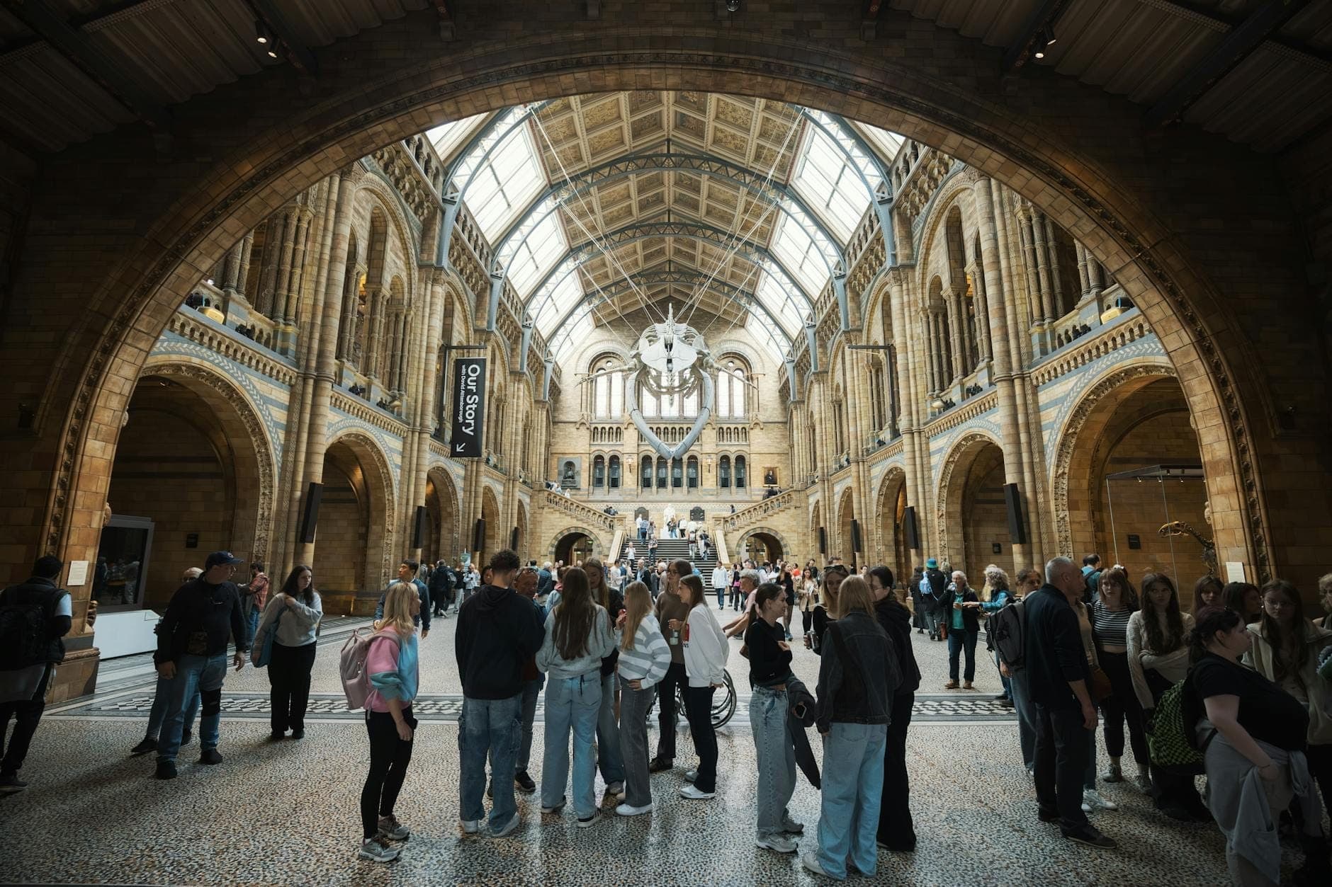 Gran multitud en el interior del gran salón del Museo de Historia Natural de Londres, con su icónico techo abovedado y su trabajo en piedra.