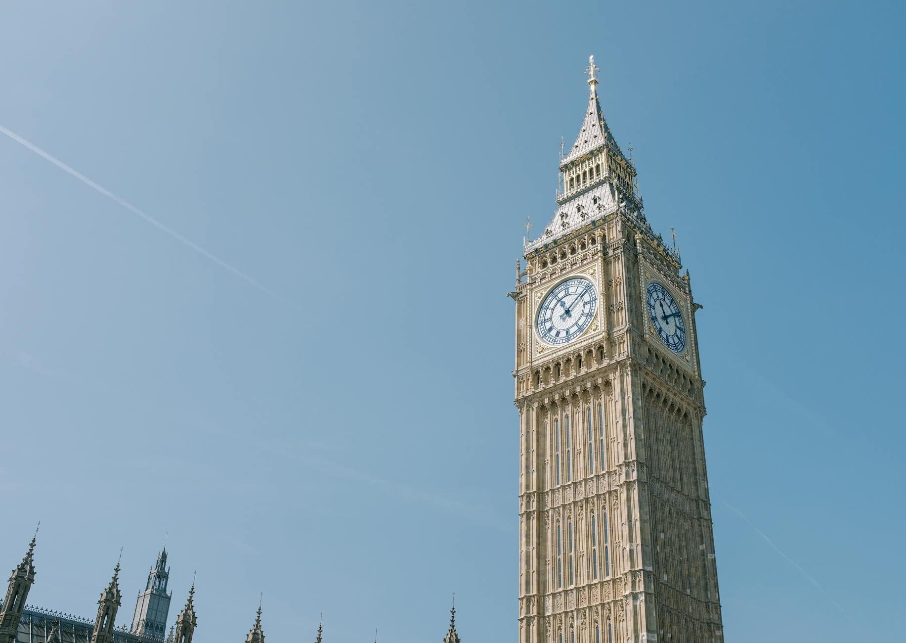 Vista panorámica del Big Ben y el Palacio de Westminster bajo un cielo azul despejado, uno de los monumentos más icónicos de Londres para los visitantes primerizos.