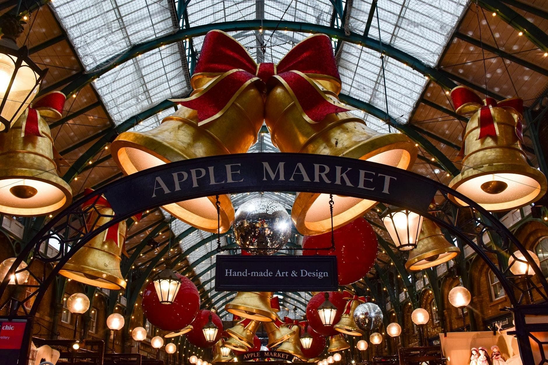 Apple Market w Covent Garden w Londynie, ozdobiony dużymi świątecznymi bombkami i kokardami pod szklanym dachem.