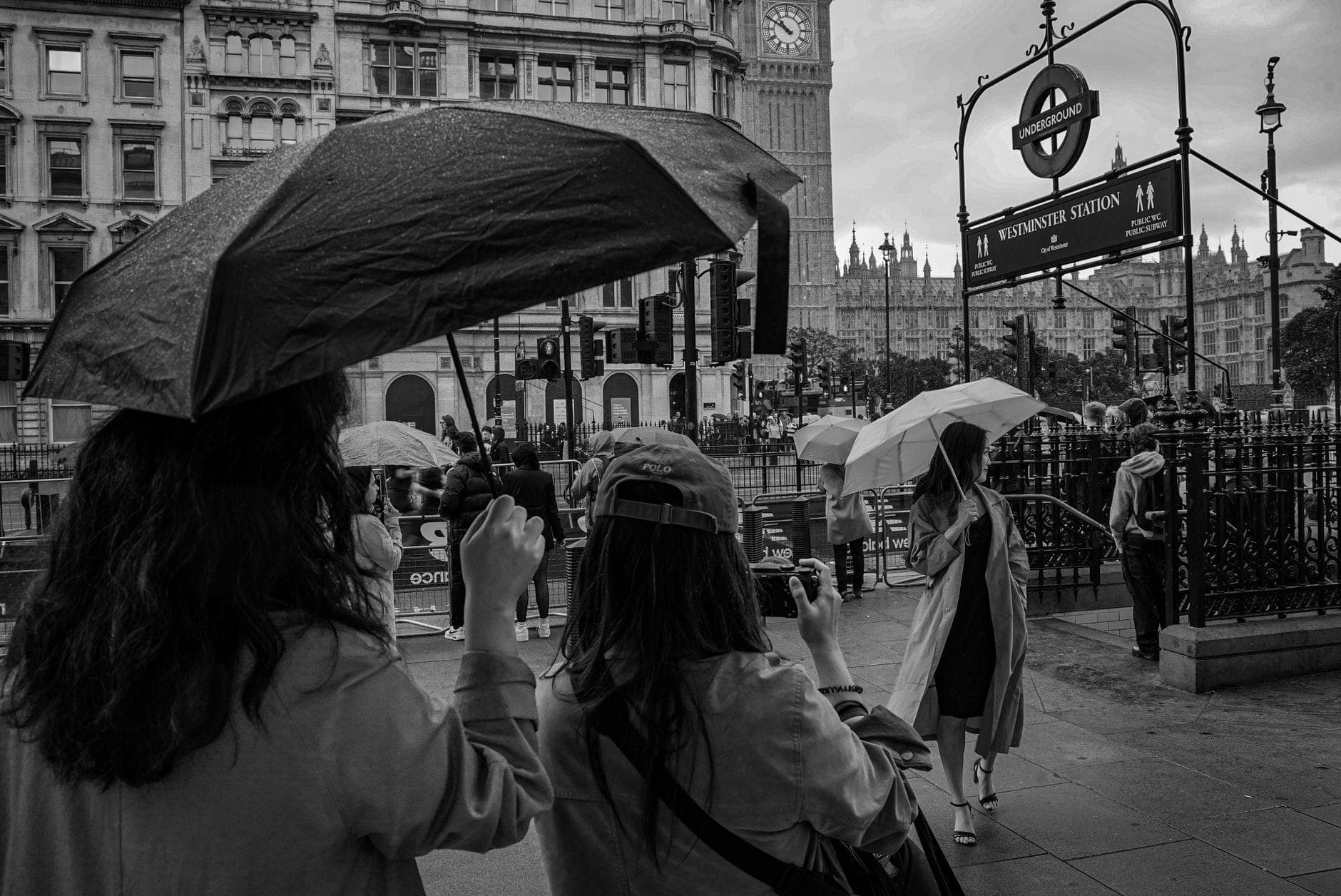 Personas con paraguas frente a la estación de Westminster y el Big Ben bajo la lluvia, mostrando el típico clima veraniego de Londres.