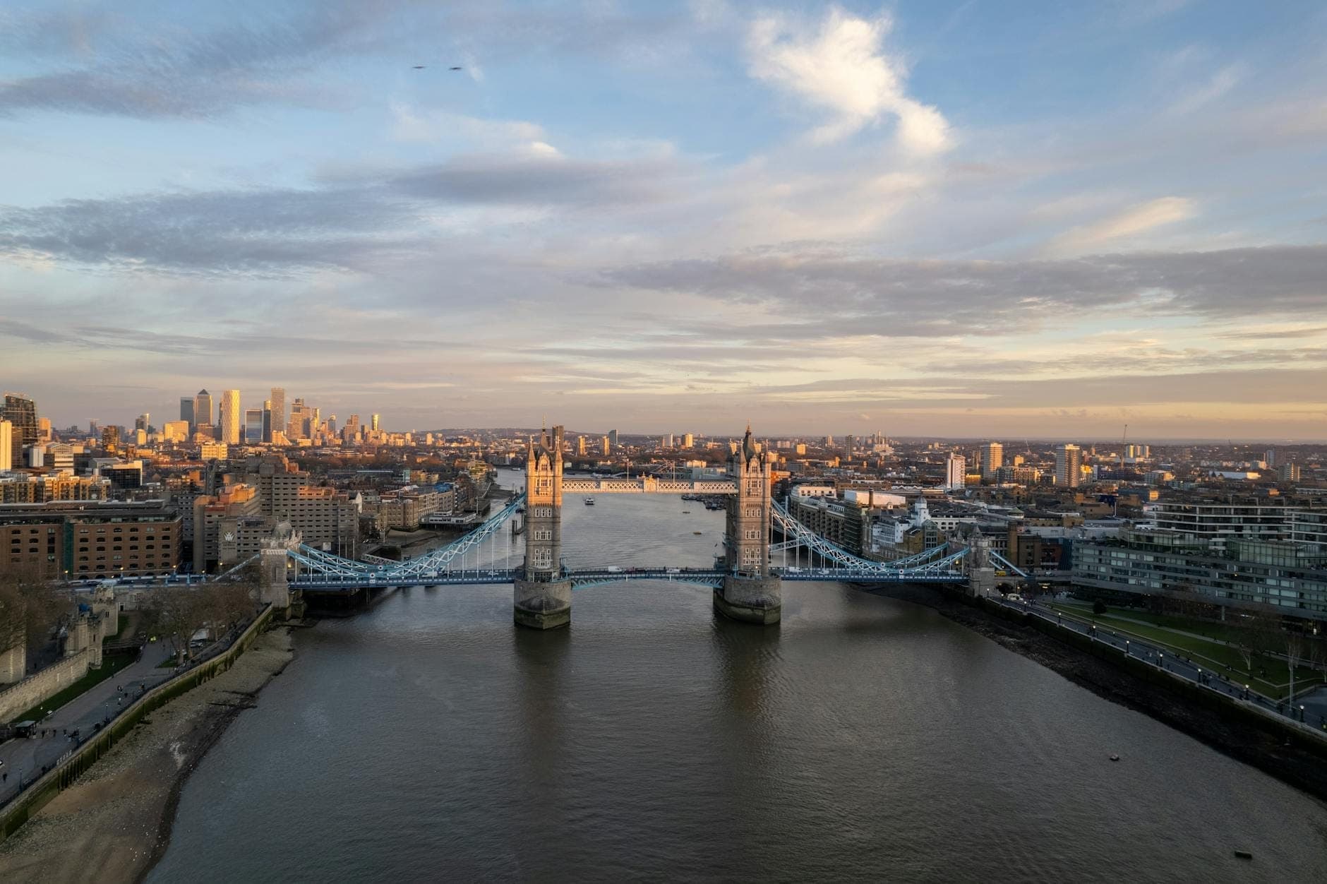 Vista aerea della Tower Bridge che attraversa il Tamigi a Londra all'alba, con lo skyline della City sullo sfondo.