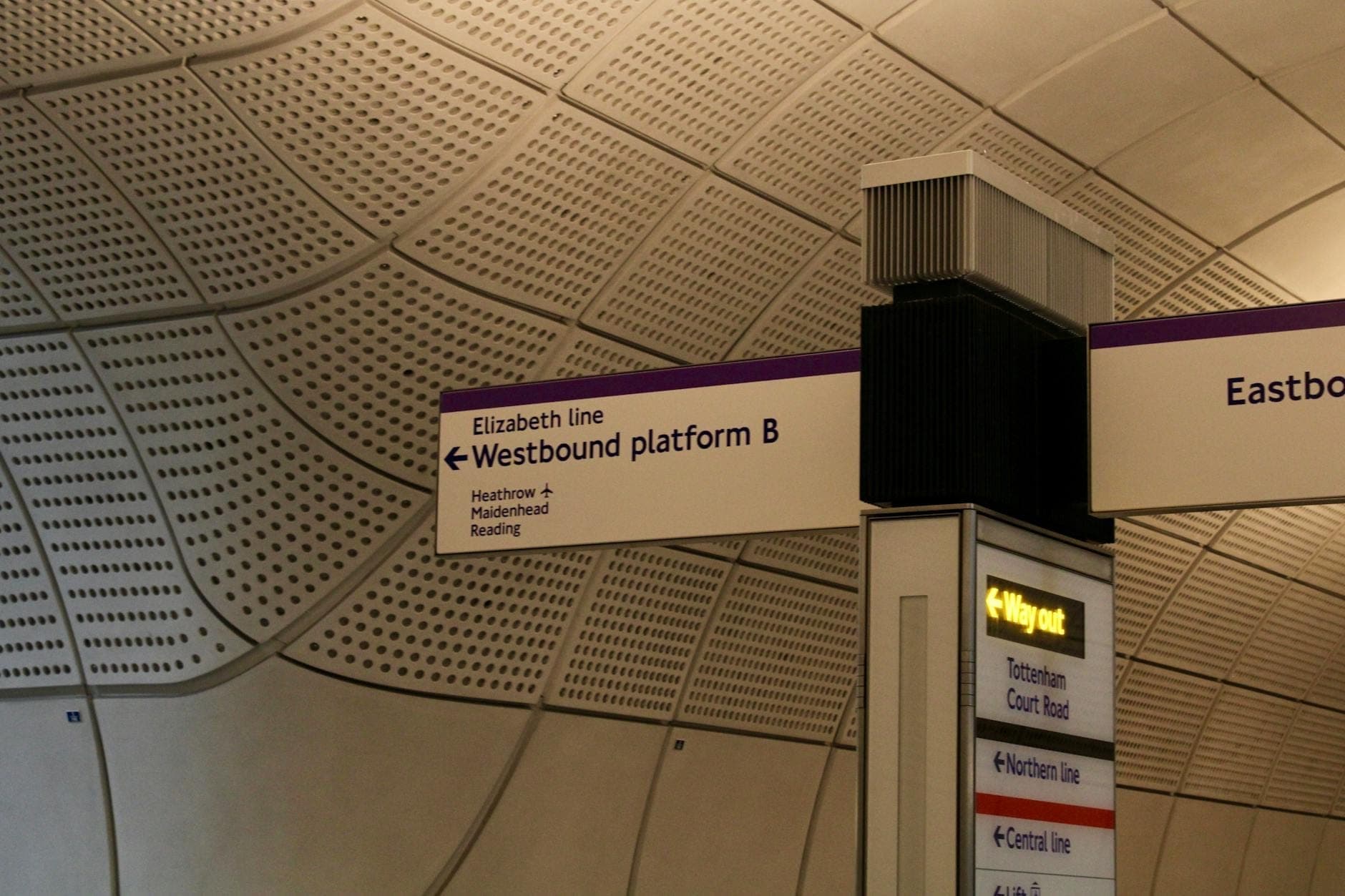 Segnaletica su una banchina della Elizabeth line di Londra che indica i treni verso Heathrow e le stazioni centrali, in una moderna stazione della metropolitana.