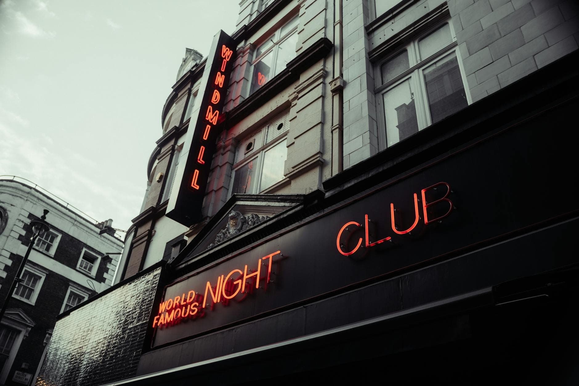 Zewnętrzna część Windmill Night Club w Londynie z podświetlonymi neonami o zmierzchu
