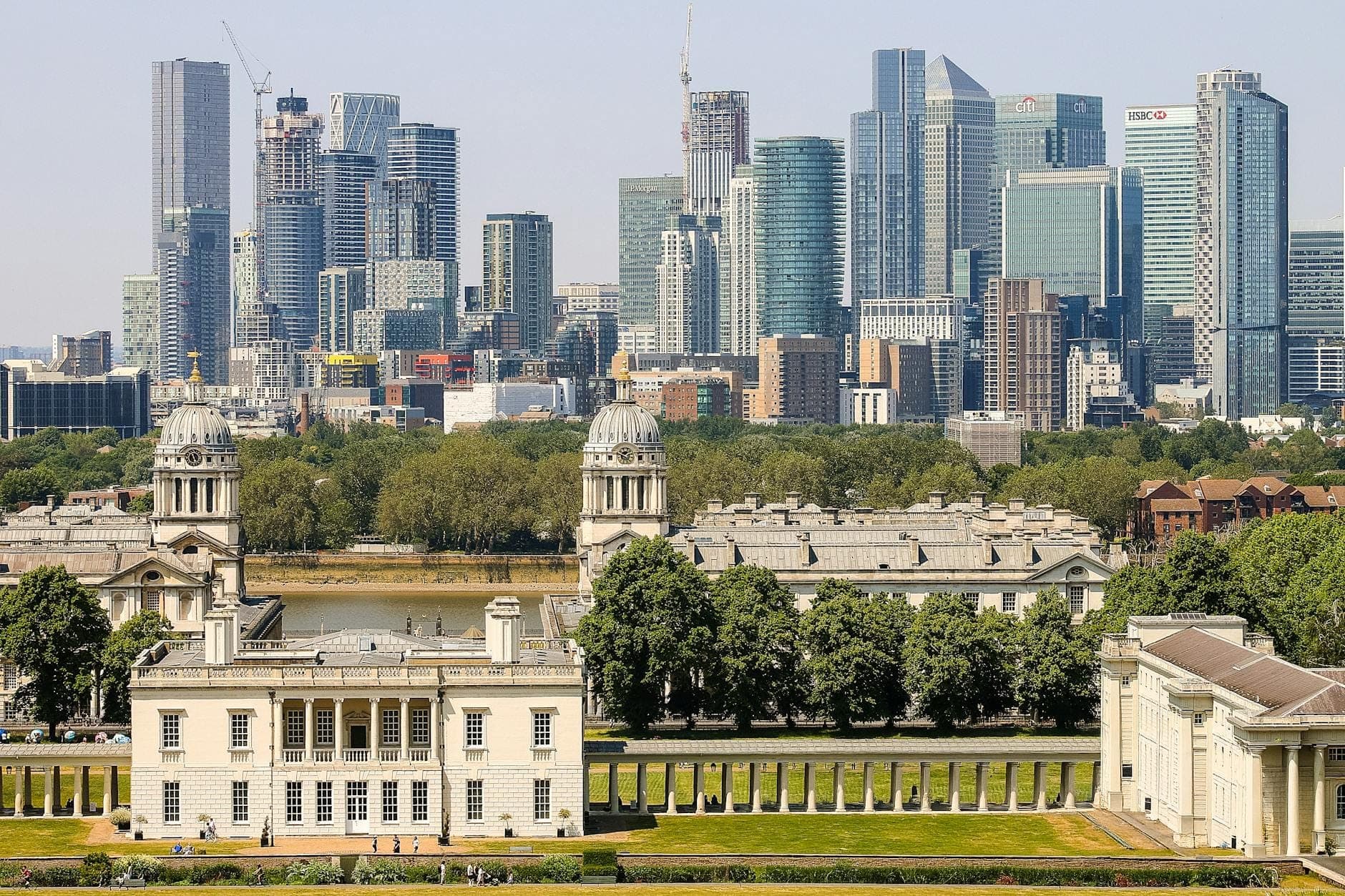 View of the Old Royal Naval College and Queen's House with the River Thames and Canary Wharf skyline in London.