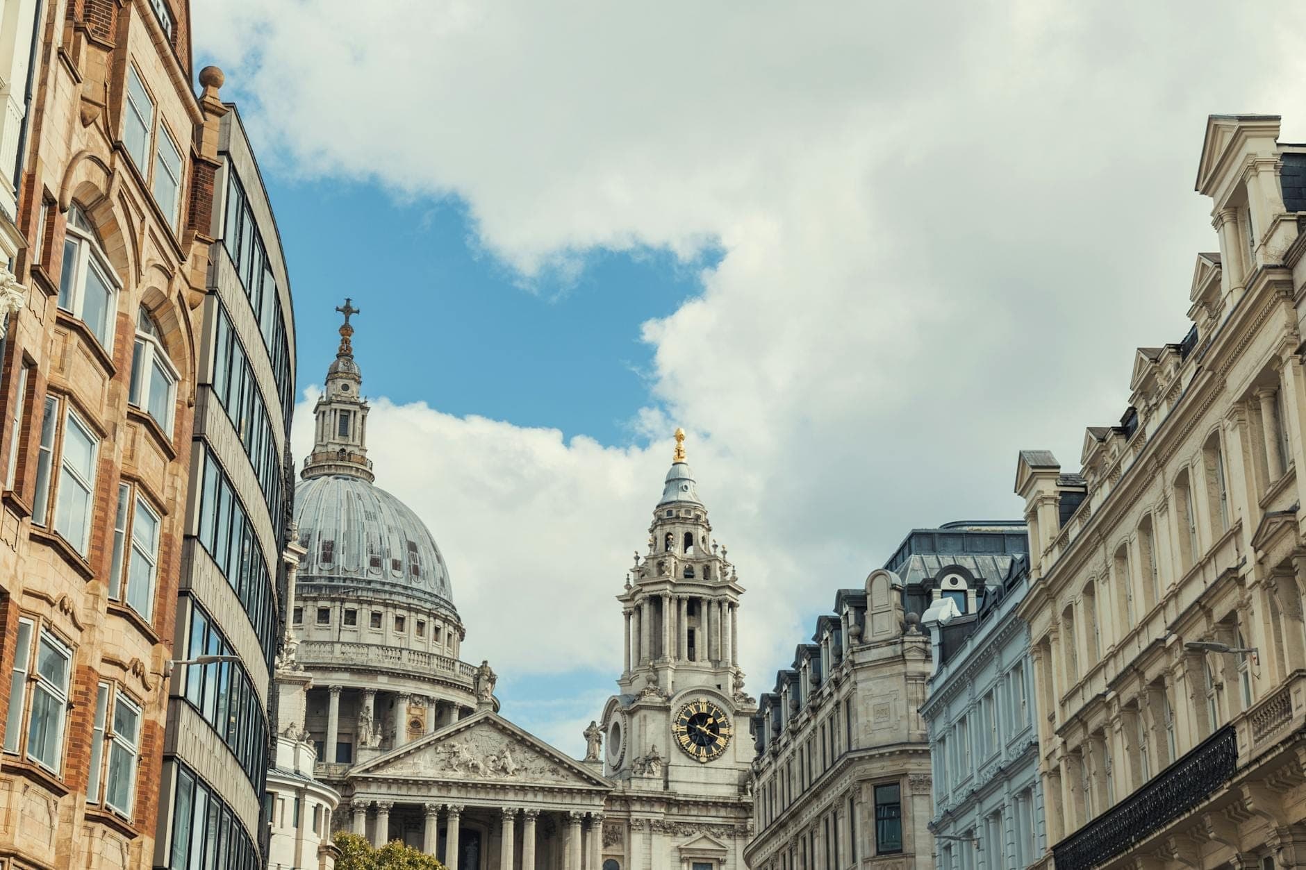 Straßenansicht der St Paul's Cathedral, umgeben von historischen Gebäuden unter blauem Himmel in der City of London.