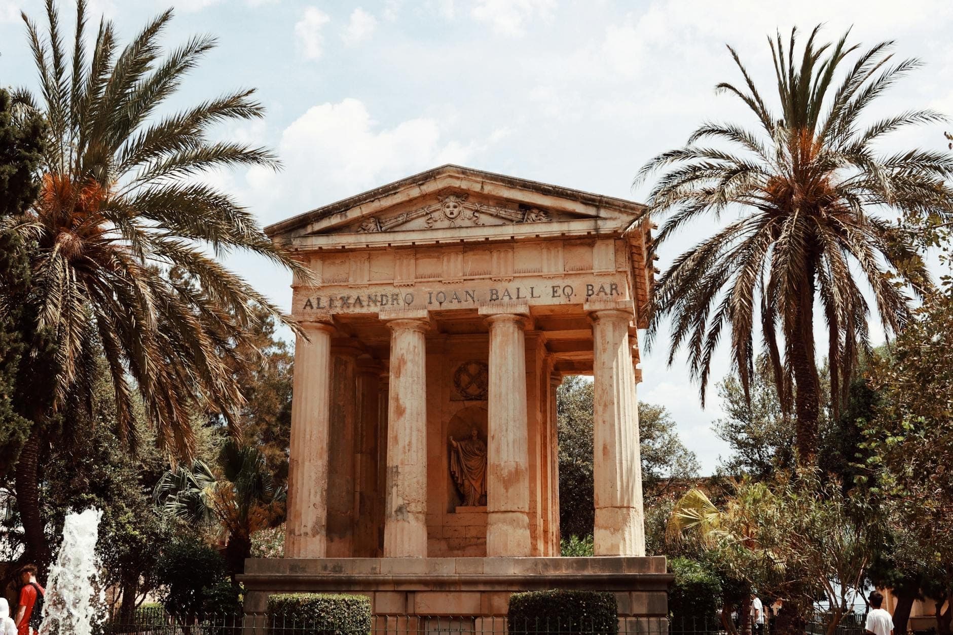 Neoklassizistisches Denkmal für Sir Alexander Ball, von Palmen eingerahmt, in den Lower Barrakka Gardens in Valletta an einem hellen Tag.