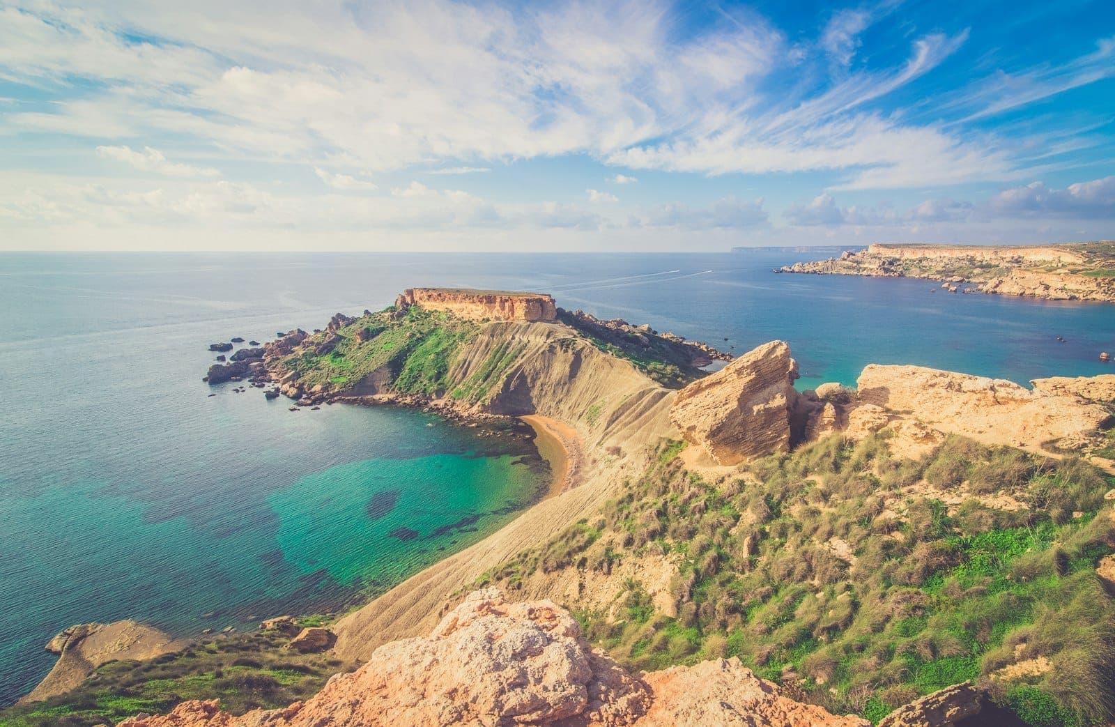 Une large baie aux eaux turquoise limpides, avec des falaises rocheuses et des collines verdoyantes le long de la côte nord de Malte, idéale pour les excursions en bateau et la baignade côtière.