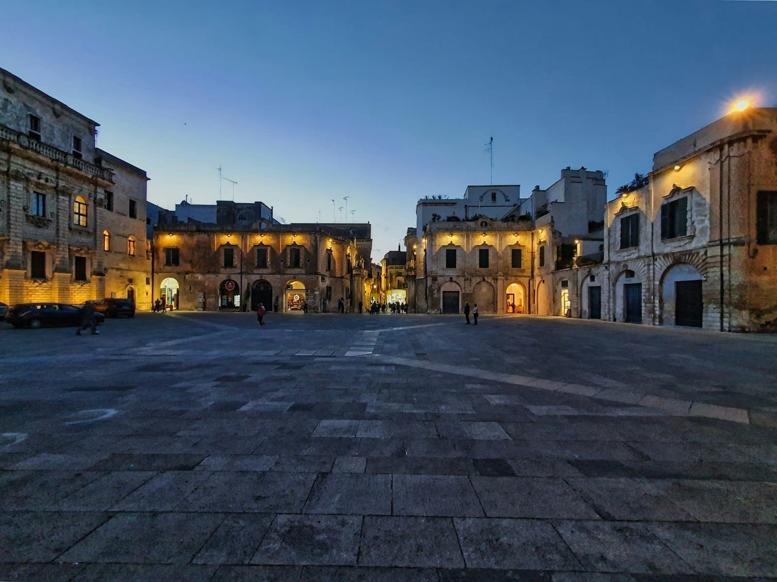 Ein weiter Steinplatz in Valletta in der Abenddämmerung, umgeben von Barockgebäuden, die sanft mit warmem Abendlicht beleuchtet sind.