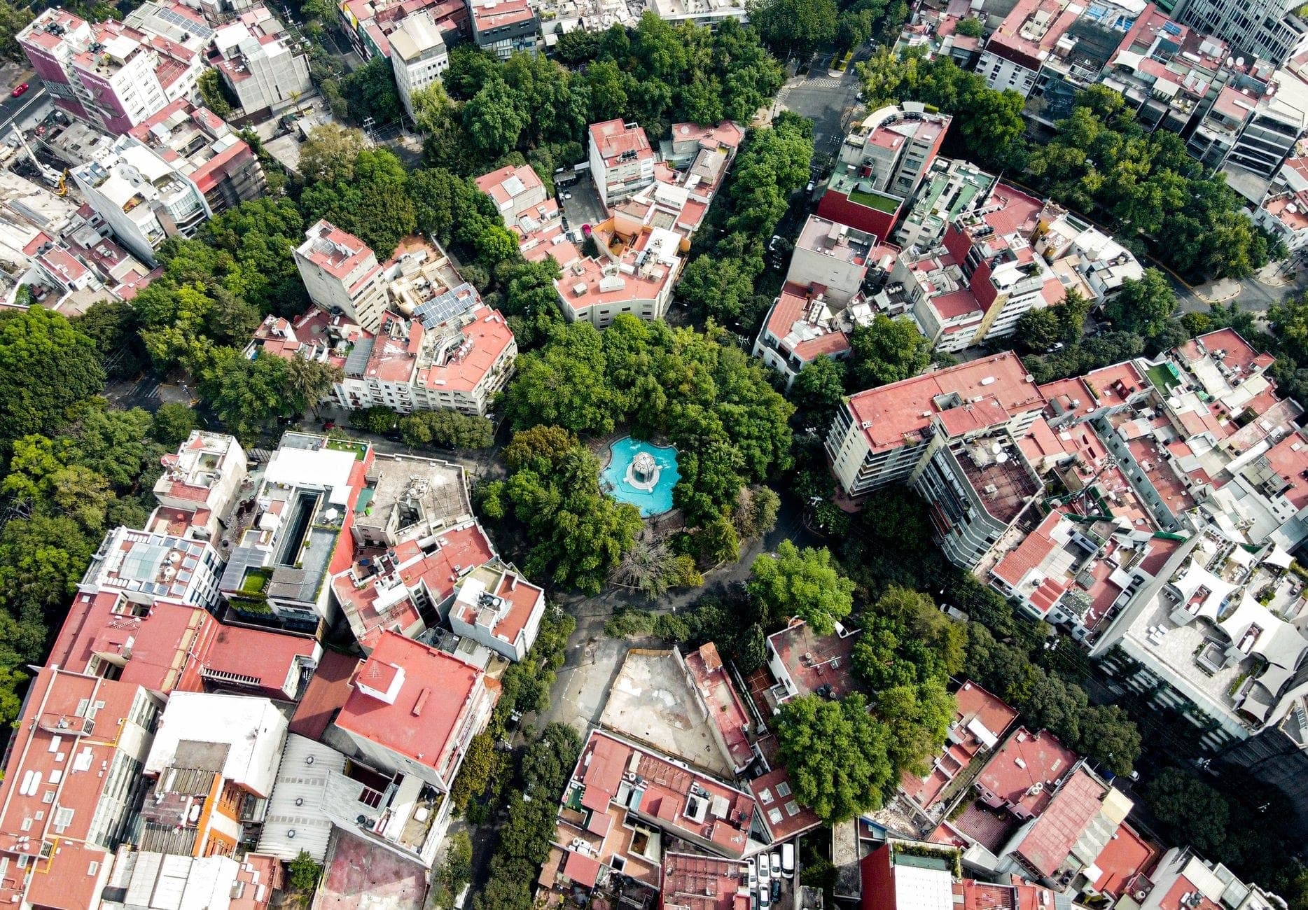 Vista aérea de Ciudad de México que muestra barrios organizados alrededor de una plaza circular arbolada con edificios y calles variadas.