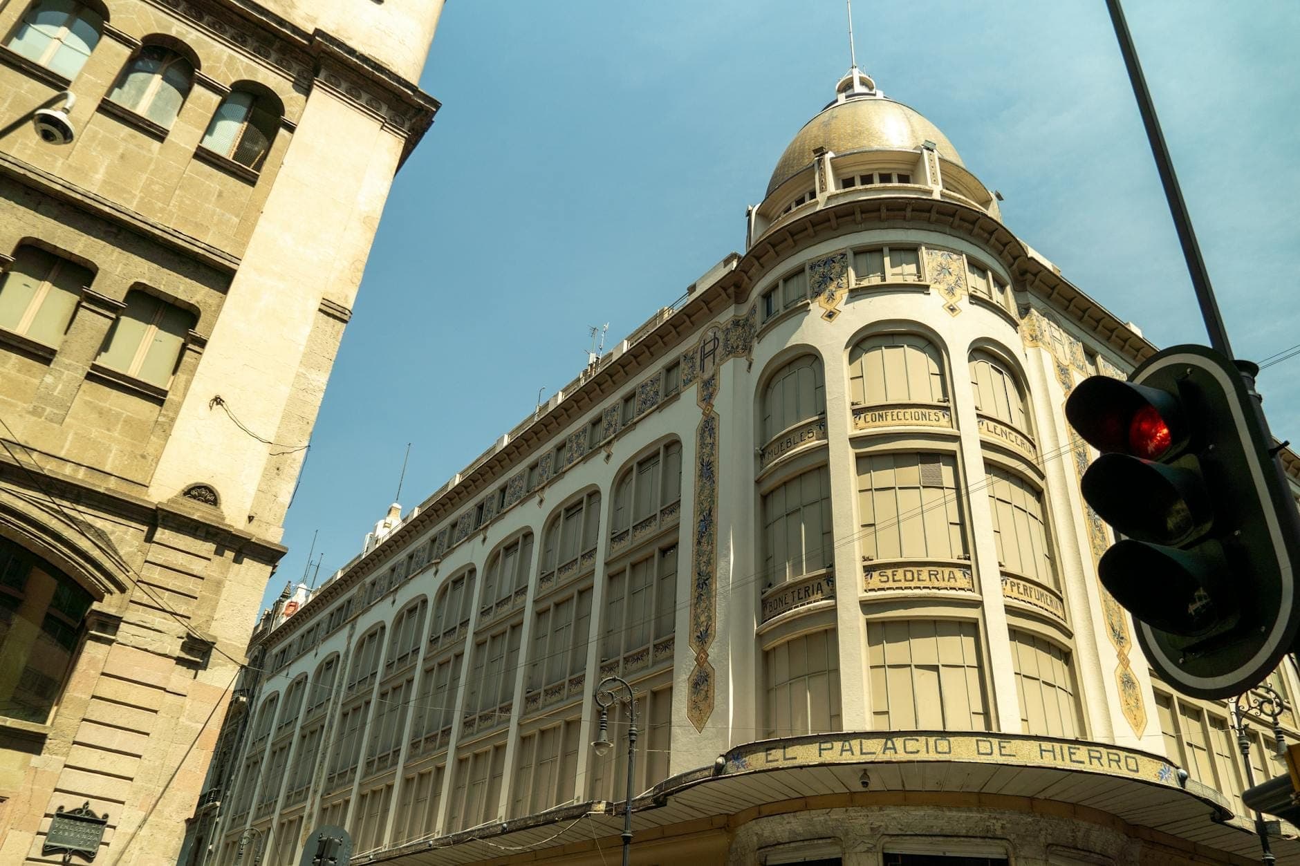 Elegante edificio histórico de El Palacio de Hierro en Ciudad de México, visto desde el nivel de la calle bajo un cielo azul.