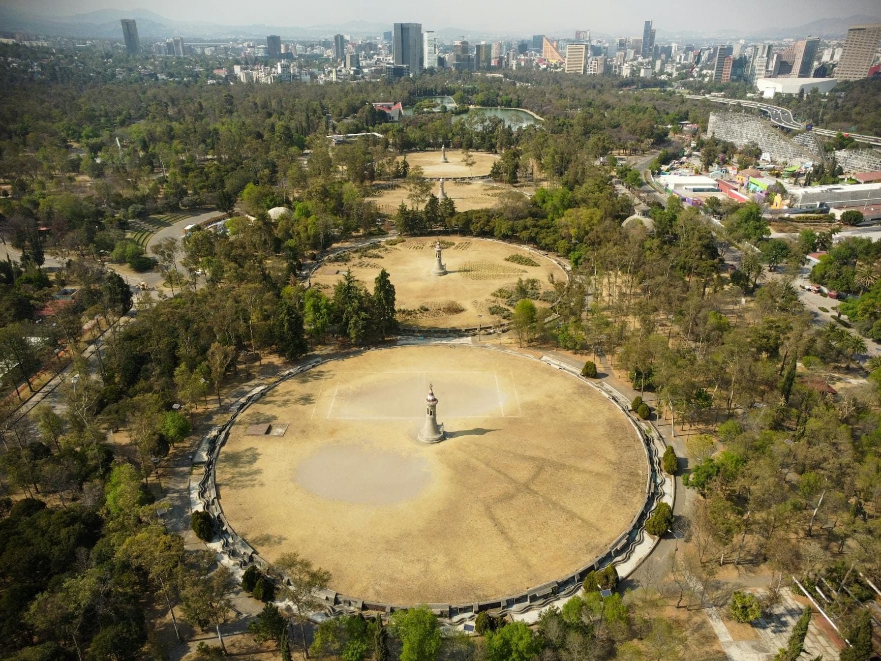 Aerial view of Chapultepec Park with spacious walkways, open greens, and city skyline on a clear day in Mexico City.