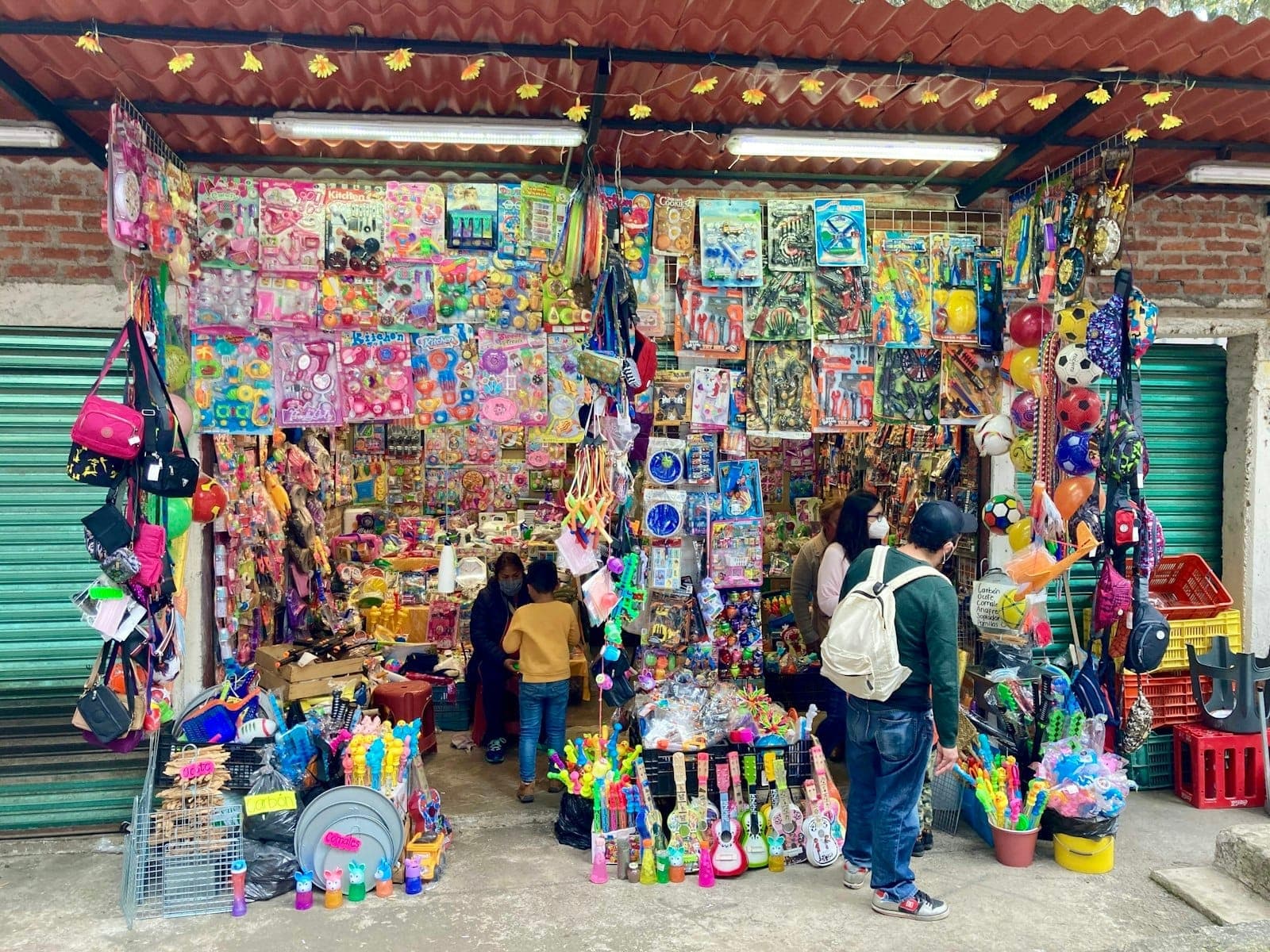 A colorful street market stall filled with toys, games, and children browsing alongside adults in Mexico City.