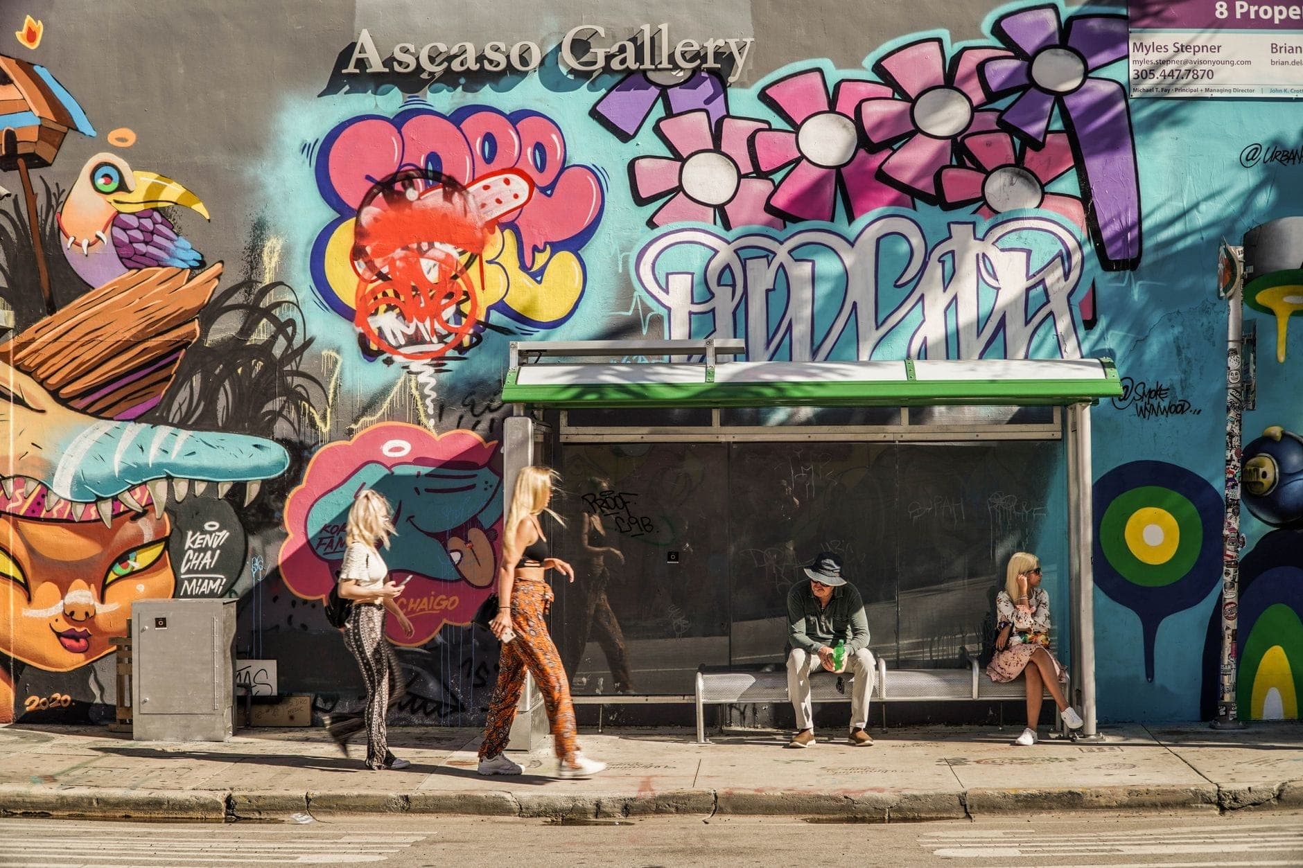 Люди, проводящие время перед красочной стеной с граффити в Ascaso Gallery в районе Wynwood Arts District в Майами