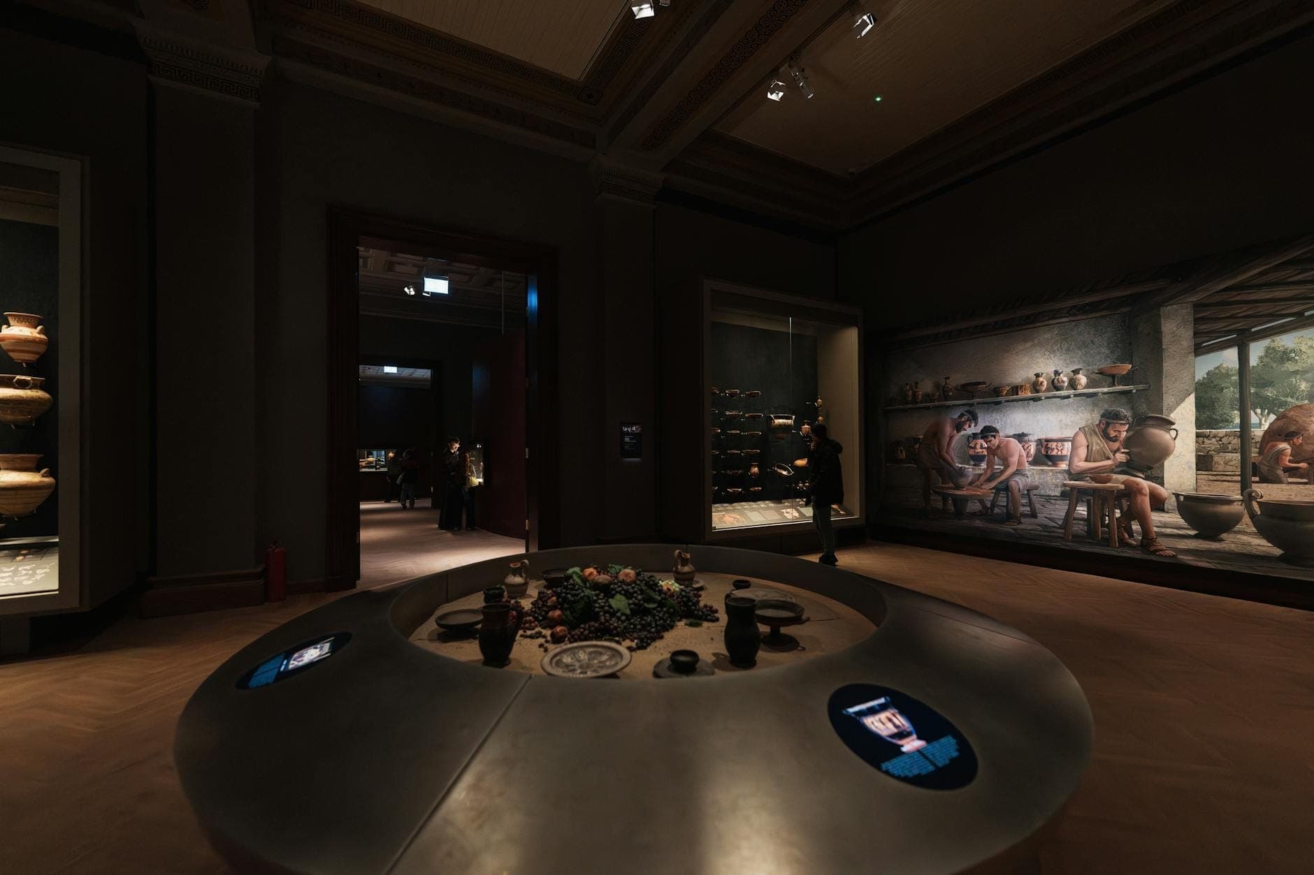 Schwach beleuchtete Galerie eines archäologischen Museums mit ausgestellten antiken Töpferwaren und Artefakten, Wandgemälde, das das minoische Leben darstellt, und Vitrinen voller Keramik.