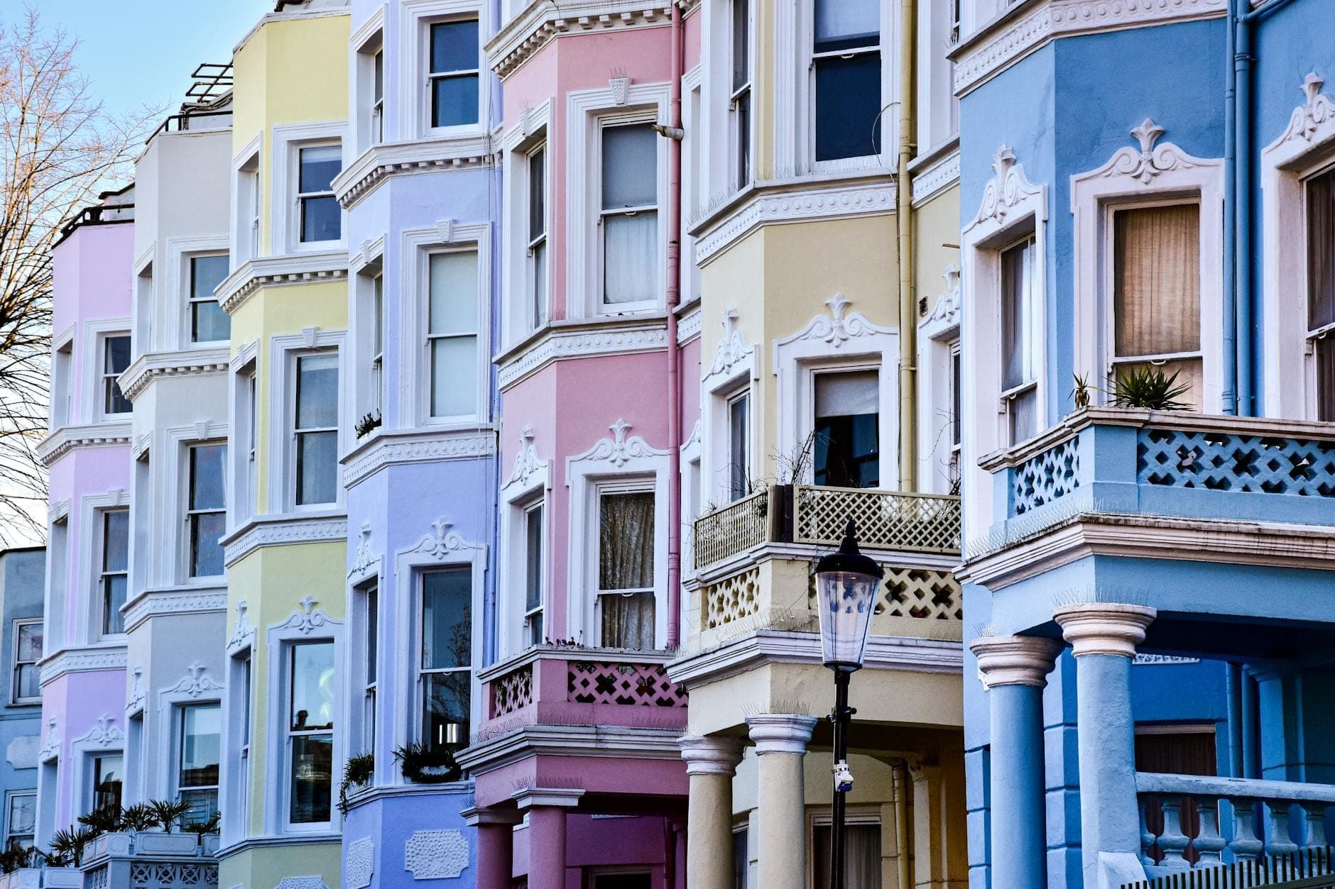 แถวบ้านทาวน์เฮาส์สีพาสเทลพร้อมรายละเอียดสไตล์วิกตอเรียนบนถนนใน London สว่างไสวภายใต้ท้องฟ้าสีฟ้า