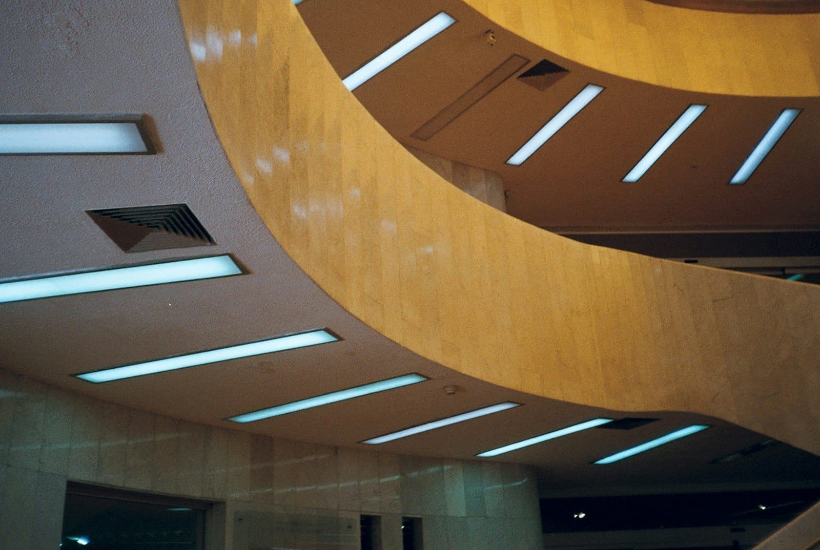 ภายในสถาปัตยกรรมโค้งของ Museo de Arte Moderno พร้อมผนังหินสีเบจและแถวของโคมไฟเพดานสีน้ำเงินสมัยใหม่