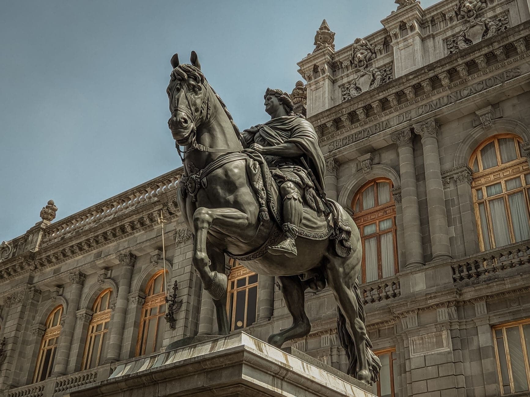 ภาพมุมกว้างของด้านหน้าพิพิธภัณฑ์ Museo Nacional de Arte สไตล์นีโอคลาสสิก พร้อมรูปปั้นม้าคู่ใจท่ามกลางท้องฟ้าใส ใจกลางเม็กซิโกซิตี้
