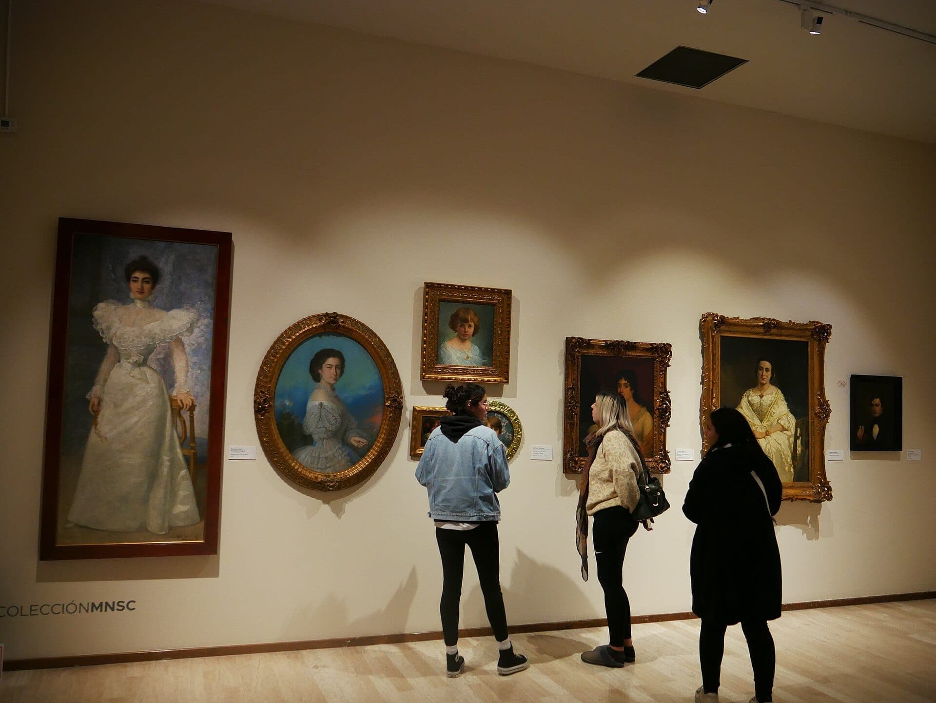 นักท่องเที่ยวชมคอลเลกชันภาพวาดพอร์ตเทรตยุโรปคลาสสิกใน Museo Nacional de San Carlos ที่จัดแสดงในกรอบทองคำประดับประดาบนผนังแกลเลอรีที่สว่างไสว