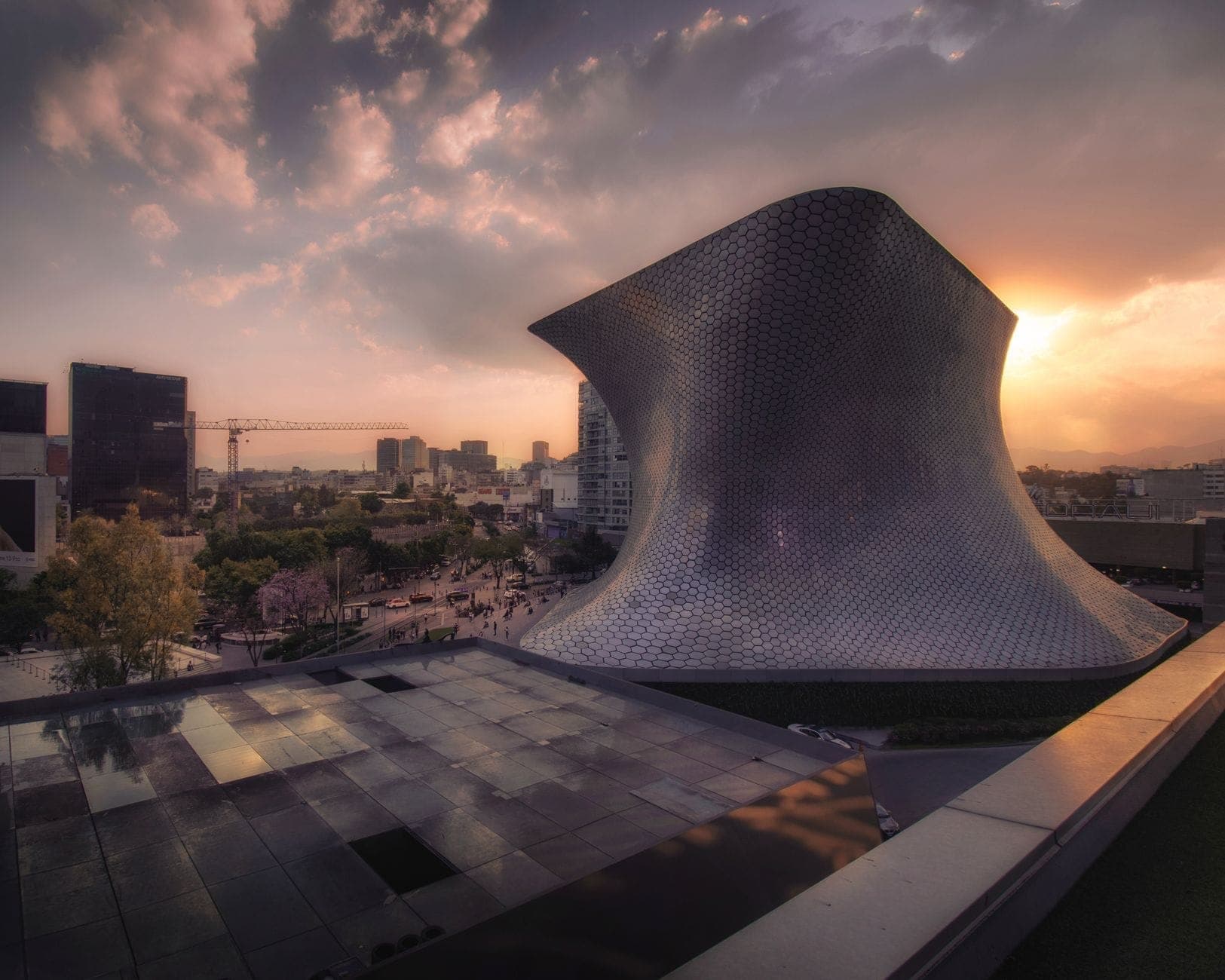 วิวยามเย็นของฟาซาดอาคารเงินโค้งสุดล้ำของ Museo Soumaya กับท้องฟ้าสวยและเมืองเม็กซิโกซิตี้ ชวนให้สำรวจพิพิธภัณฑ์ศิลปะฟรีแห่งนี้