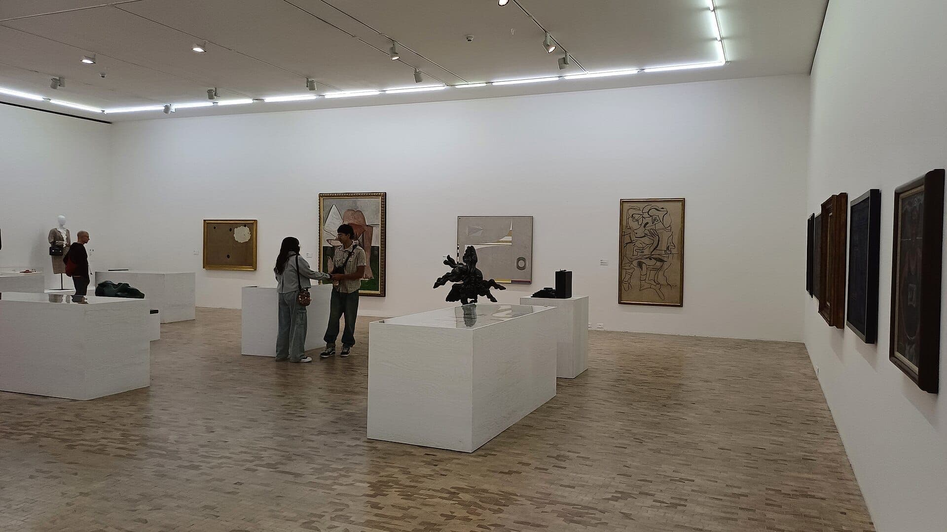 วิวภายในของ Museo Tamayo Arte Contemporáneo พร้อมงานศิลปะสมัยใหม่ ผนังสีขาว พื้นไม้ และผู้เยี่ยมชมที่ชื่นชมนิทรรศการ