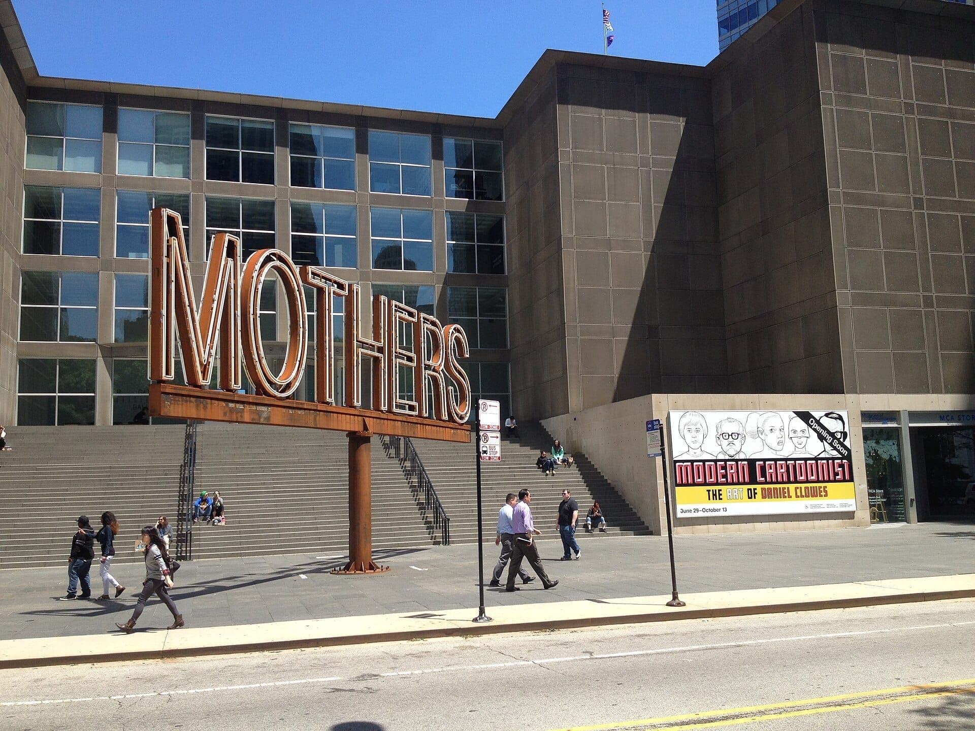 Exterior of the Museum of Contemporary Art Chicago with the large MOTHERS sculpture, sunny day, and people walking near museum steps.
