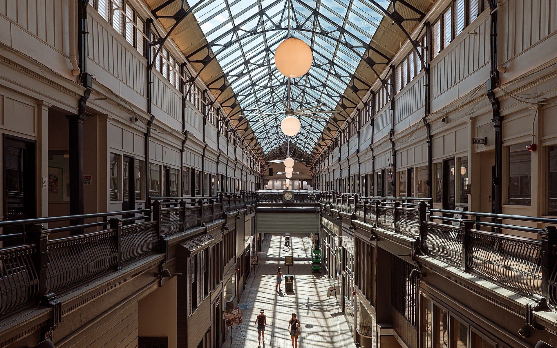 Interior view of the Nashville Arcade featuring a glass roof, vintage railings, and people walking below in natural daylight.