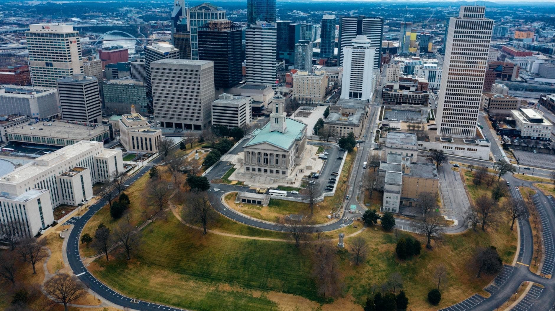 Luftaufnahme des Tennessee State Capitol, umgeben von Straßen, Gebäuden der Innenstadt von Nashville und Grünanlagen, als Ausgangspunkt einer Autorundfahrt.