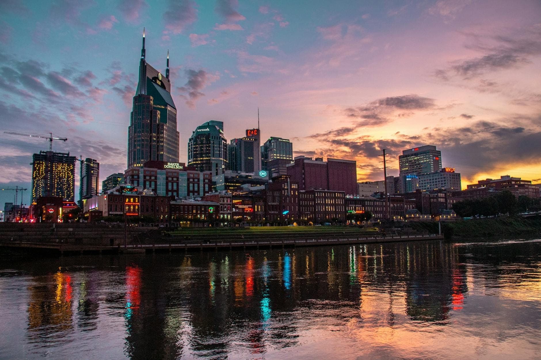 Horizonte de Nashville al atardecer con nubes dramáticas y reflejos en el río, ilustrando el cambio de clima y las condiciones atmosféricas.