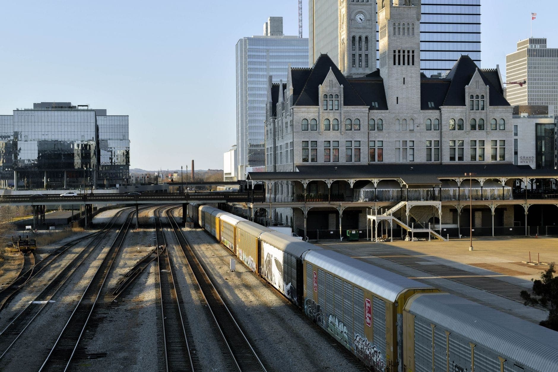 Vías de tren y un tren junto a la histórica Union Station de Nashville en el centro de la ciudad con edificios modernos al fondo.