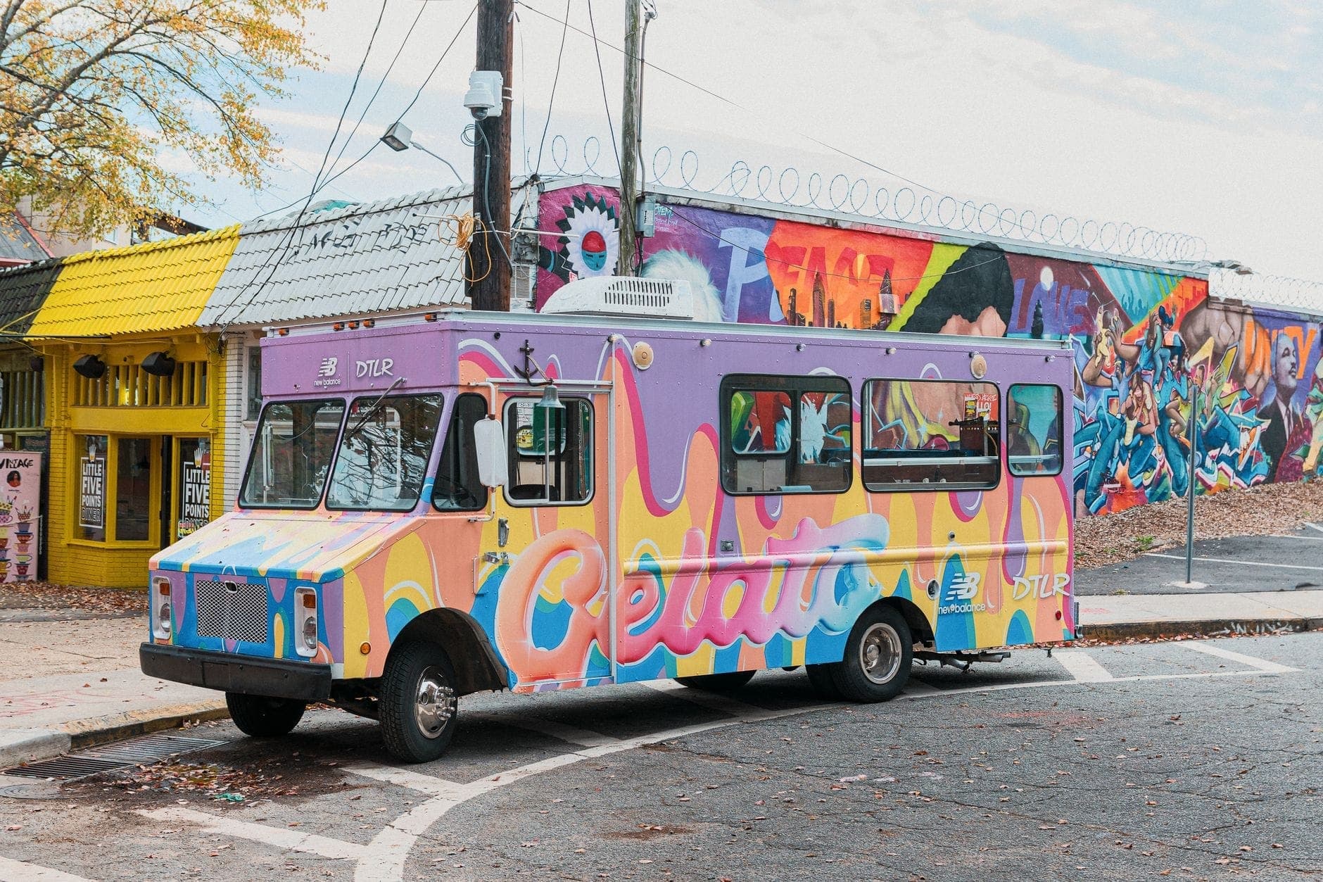 Kolorowa ciężarówka z lodami gelato zaparkowana na ulicy przed budynkami pokrytymi muralami, żółtą witryną sklepową i tętniącym życiem handlem indie typowym dla East Nashville.