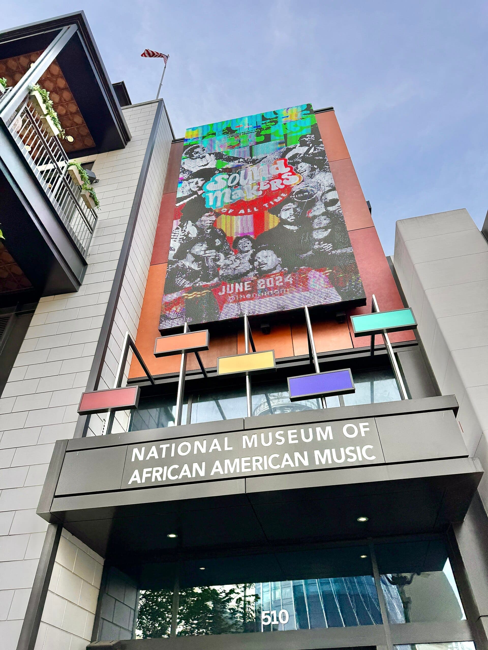 Entrance of the National Museum of African American Music in Nashville with colorful marquee and modern architectural details under a blue sky.