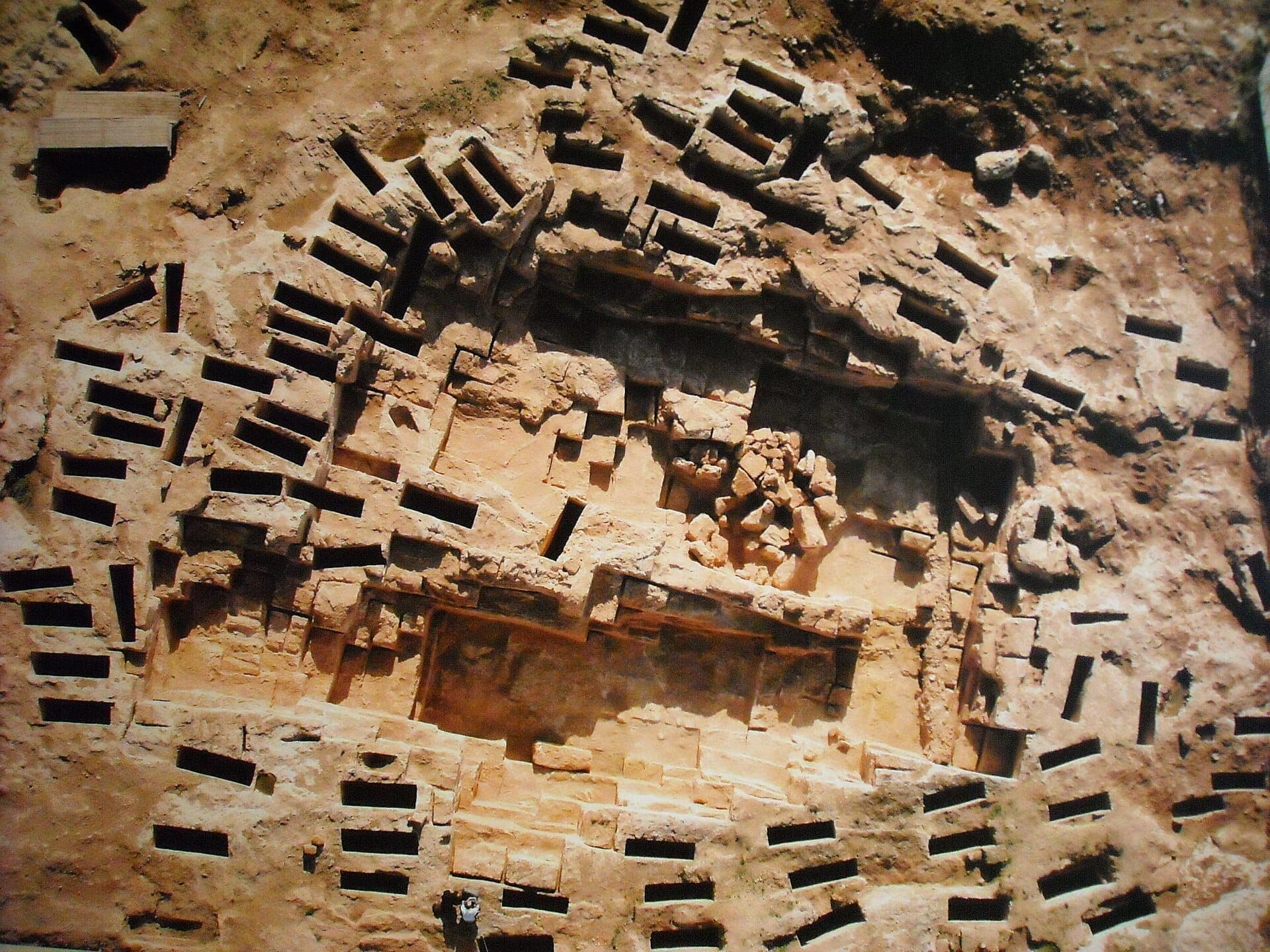 Vista aérea de las tumbas rupestres de la Necropoli di Tuvixeddu en Cagliari, con cámaras funerarias rectangulares talladas en caliza beige.