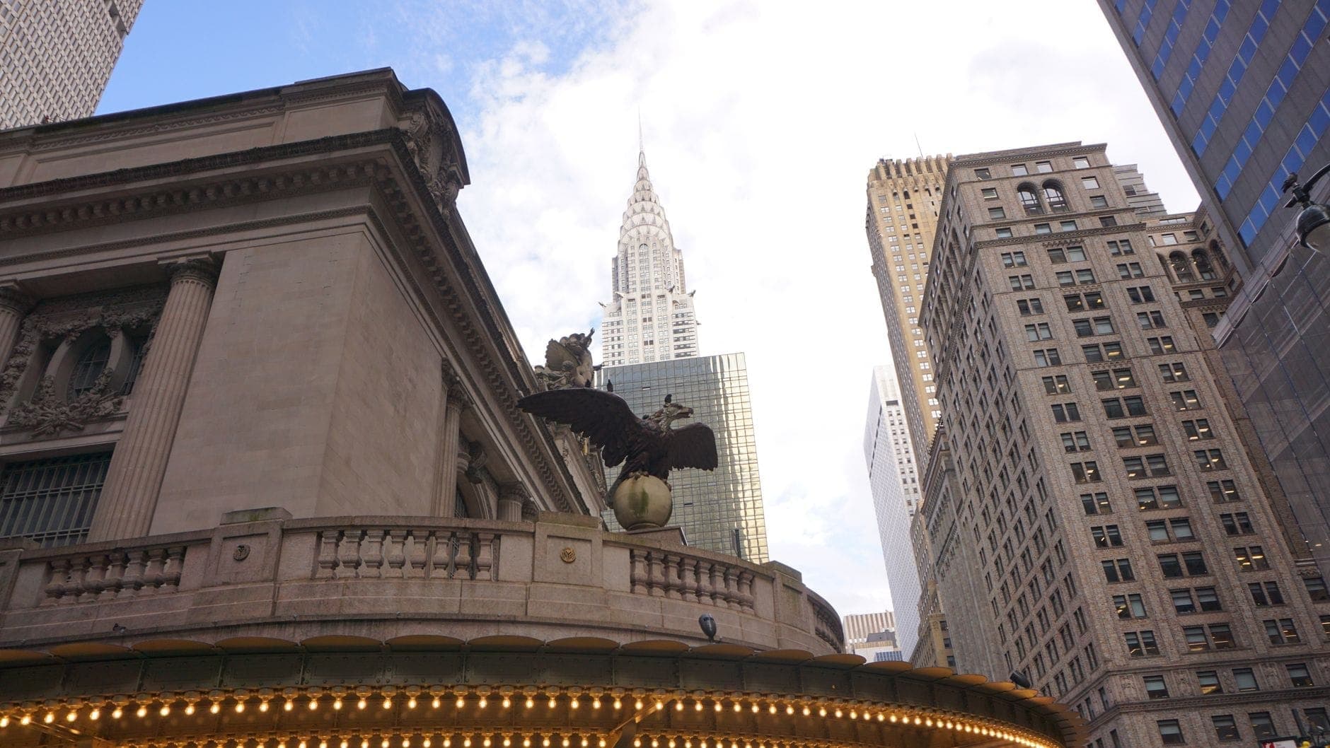 วิวของ Grand Central Terminal พร้อมรูปปั้นนกอินทรีในเบื้องหน้า และ Chrysler Building ที่สูงตระหง่านท่ามกลางตึกระฟ้าของ Midtown ใต้ท้องฟ้าสดใส