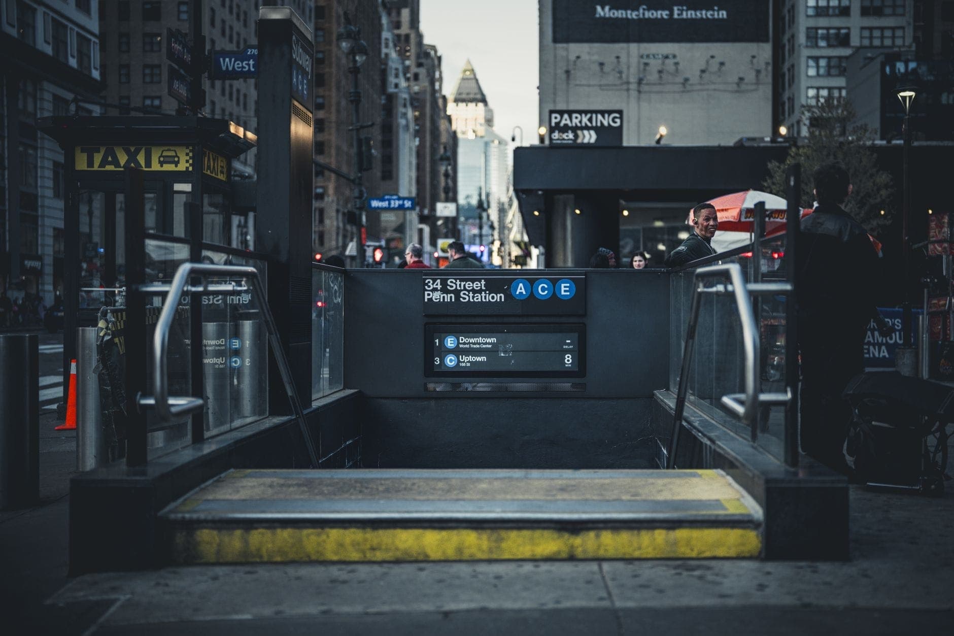 ทางเข้าสถานีรถไฟใต้ดิน Penn Station บน 34th Street พร้อมผู้คนและอาคารในนครนิวยอร์ก