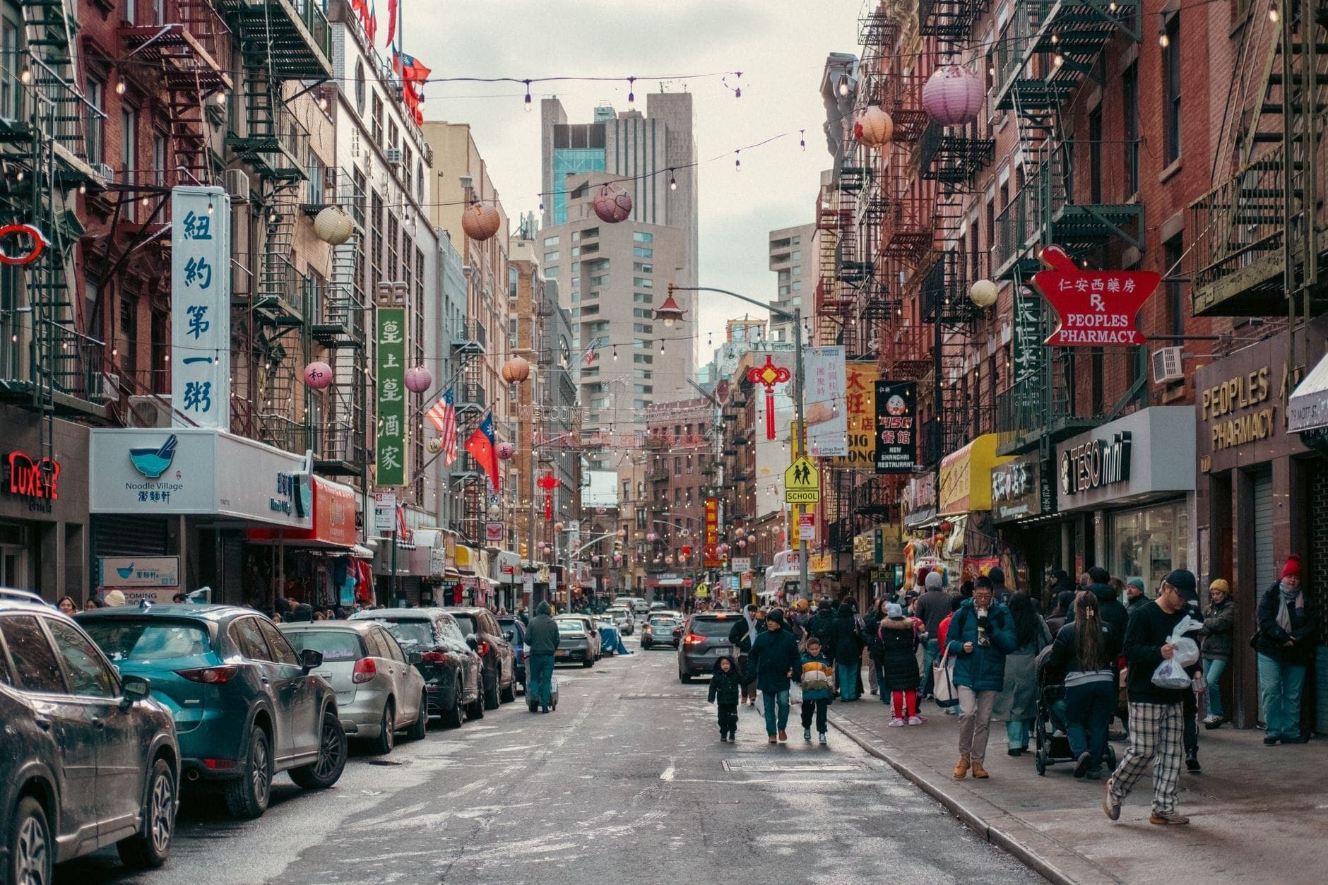 ภาพถนนในย่าน Chinatown ของ New York City ที่คึกคักด้วยร้านค้าหลากหลาย ผู้คนสัญจร และโคมไฟแขวน สะท้อนถึงวัฒนธรรมอาหารหลากหลายชาติพันธุ์ของเมือง