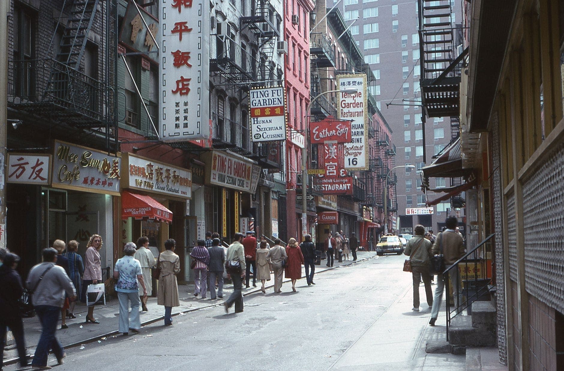 ถนนที่คึกคักใน Chinatown ของ New York City มีผู้คนเดินผ่านไปมา ป้ายร้านอาหารจีน และอาคารในเมือง